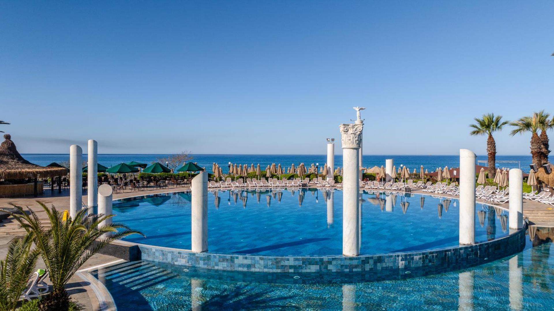 Starlight Resort galvenais baseins ar dekoratīvām kolonnām antīkā stilā, saulessargiem un skatu uz Vidusjūru