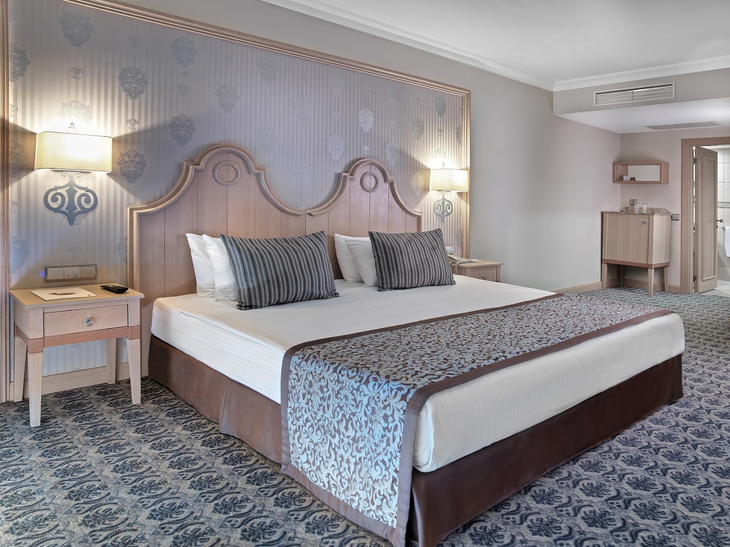 Starlight Resort viesnīcas numura interjers ar lielu gultu, dekoratīvām tapetēm un mīksto grīdas segumu klasiskā stilā