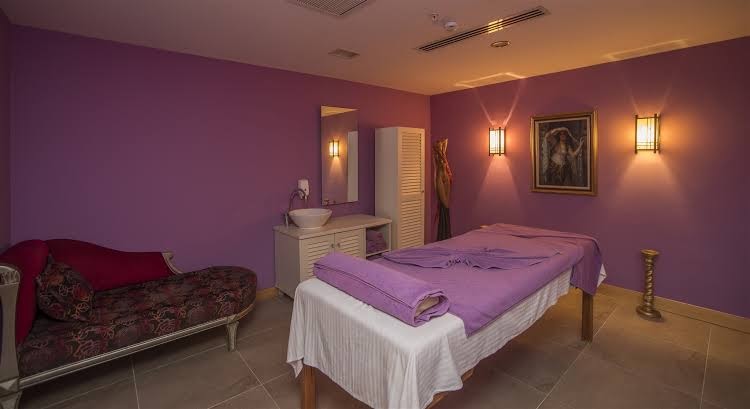 Starlight Resort spa centra masāžas telpa ar violetām sienām, ērtu kušeti un relaksējošu apgaismojumu mierpilnai atpūtai