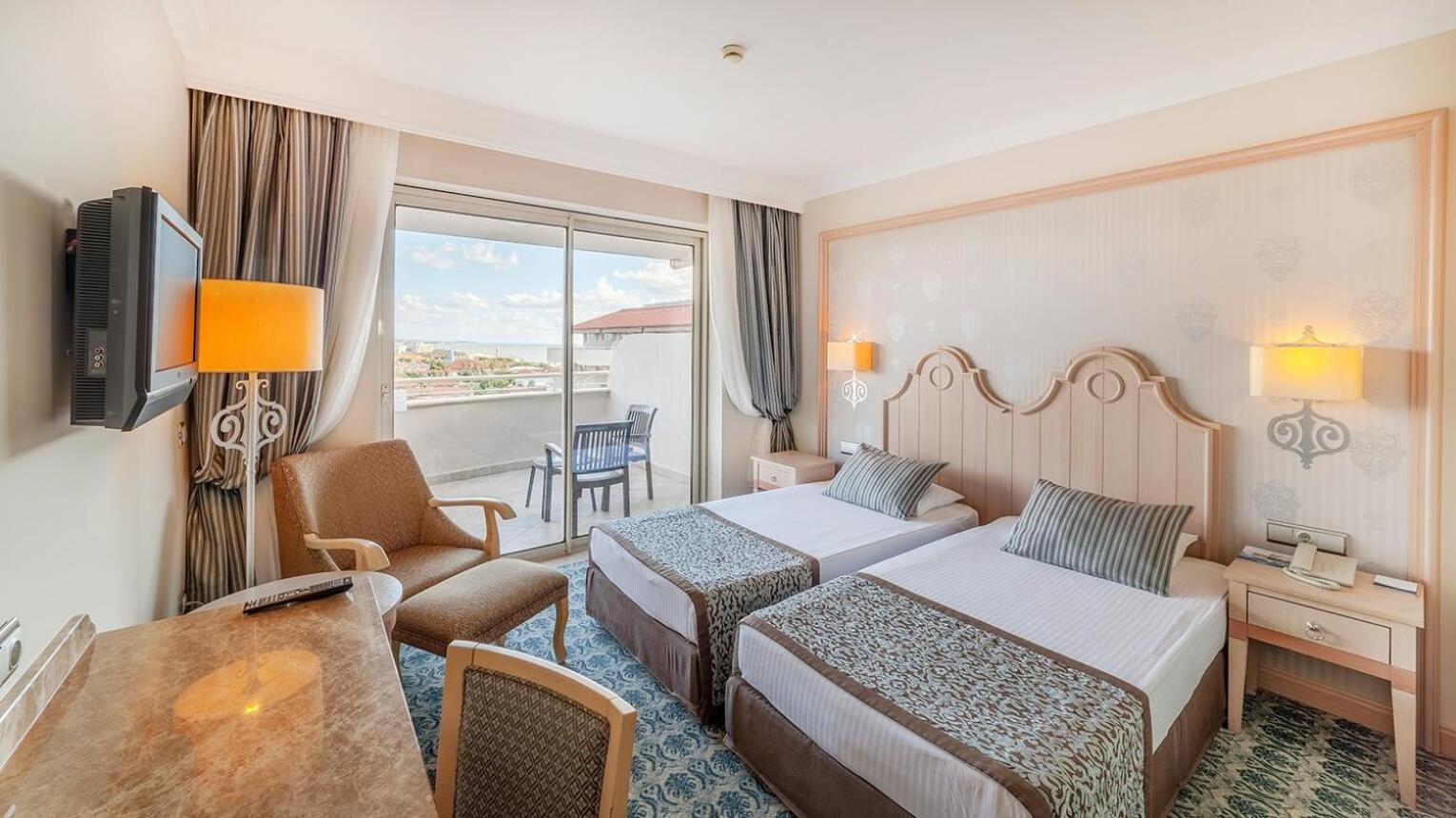 Starlight Resort numurs ar divām atsevišķām gultām, atpūtas krēslu un balkonu ar skatu uz kūrorta teritoriju un jūru