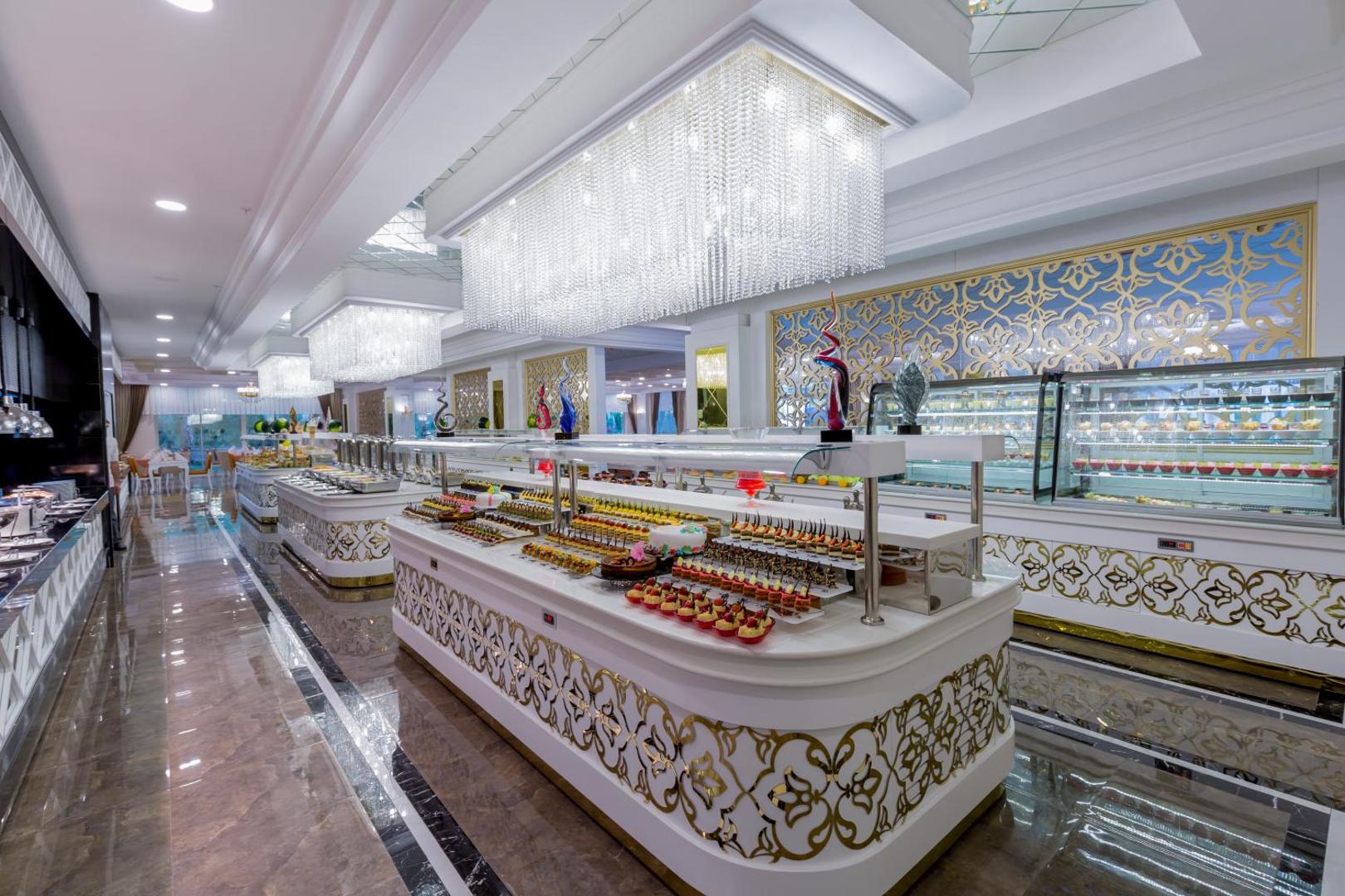 Side Royal Palace galvenā restorāna bufetes zona ar plašu desertu izvēli un greznām kristāla lustrām