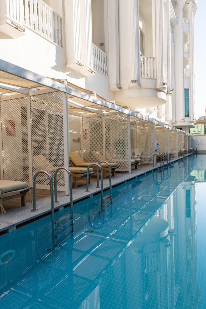 Side Royal Palace swim-up numuru pieeja baseinam ar privātām sauļošanās gultām zem nojumes — moderna viesnīcas ēka un dzidrs ūdens