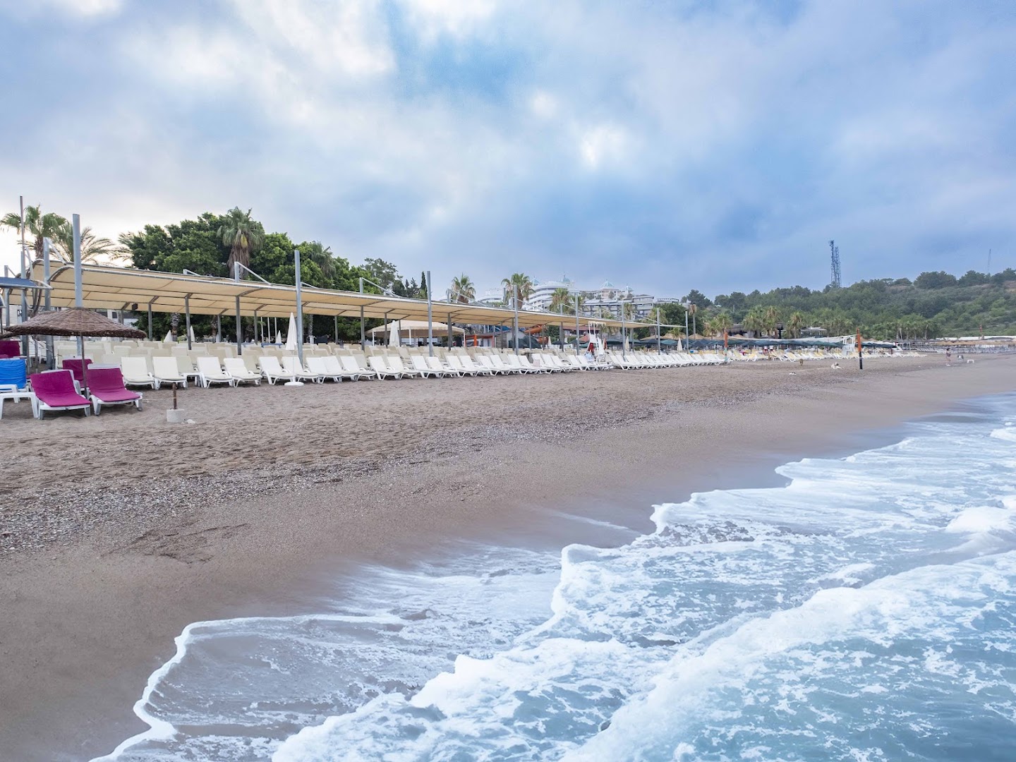 Sealife Buket Resort & Beach plašā smilšu un oļu pludmale ar gariem sauļošanās krēslu rindām un nojumēm
