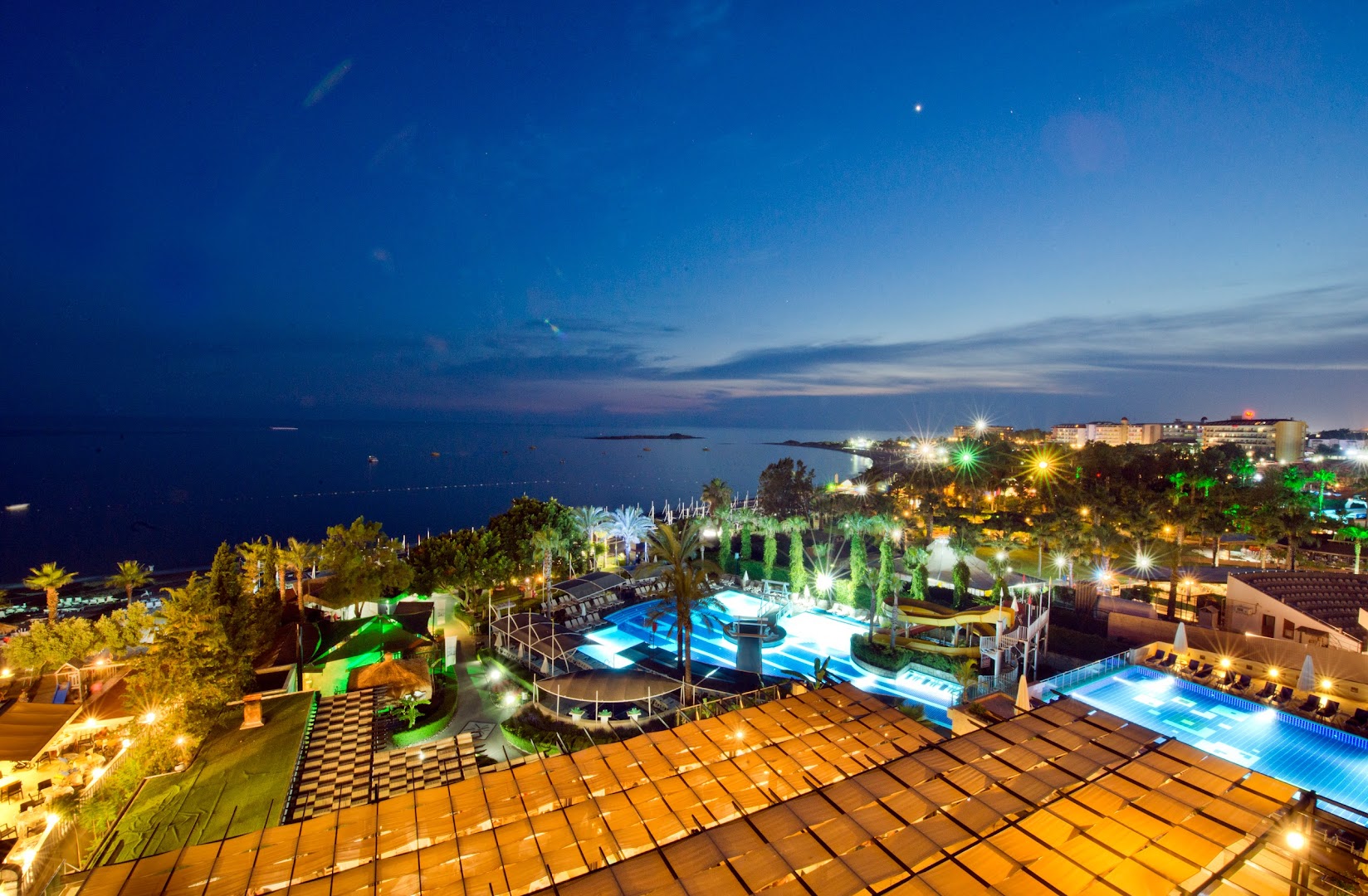 Sealife Buket Resort & Beach panorāmas skats vakarā uz baseiniem, dārzu un Vidusjūras piekrasti Alānijā, Turcijā