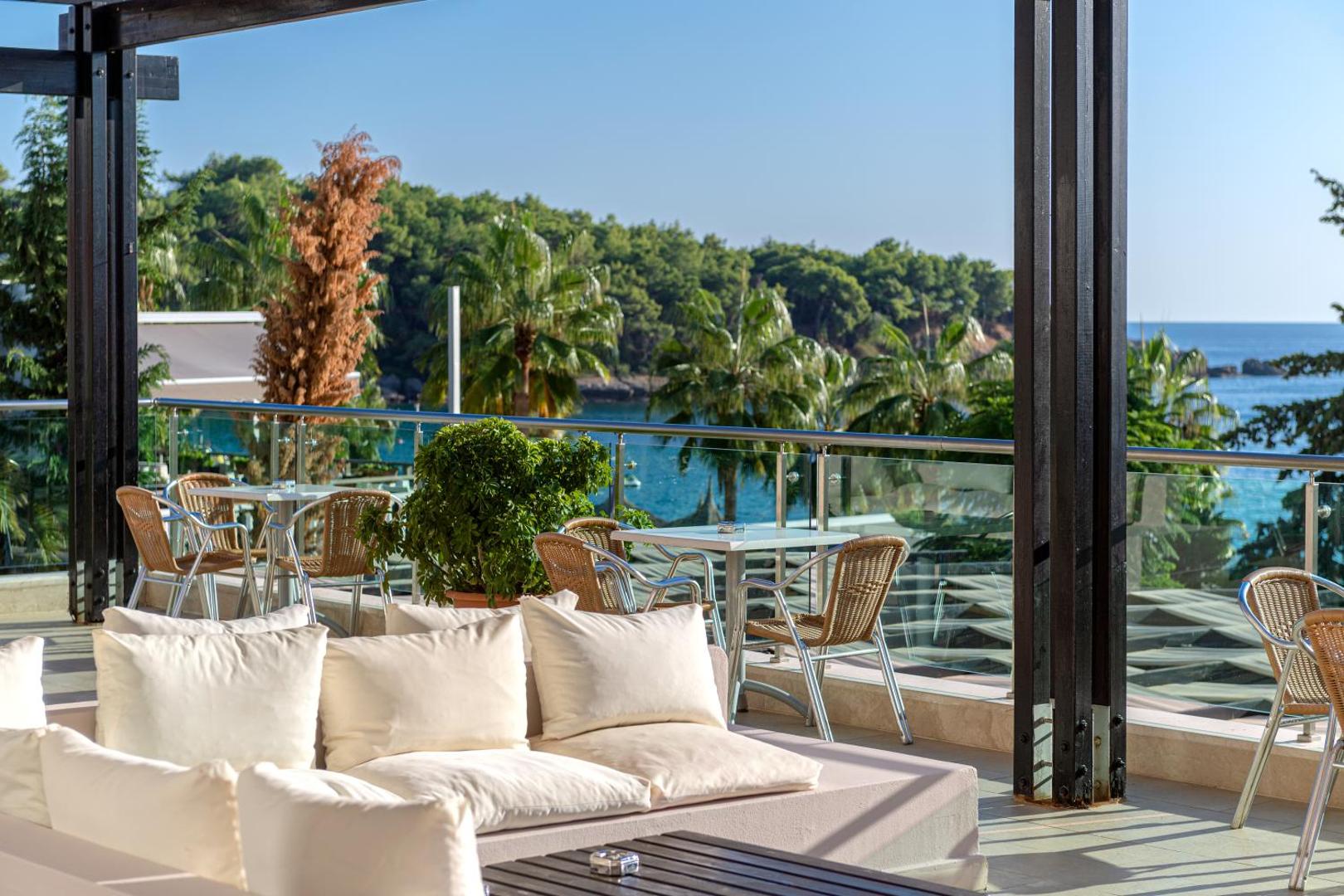 Skats no Sealife Buket Resort & Beach terases uz Vidusjūras līci un zaļojošu priežu mežu saulainā dienā