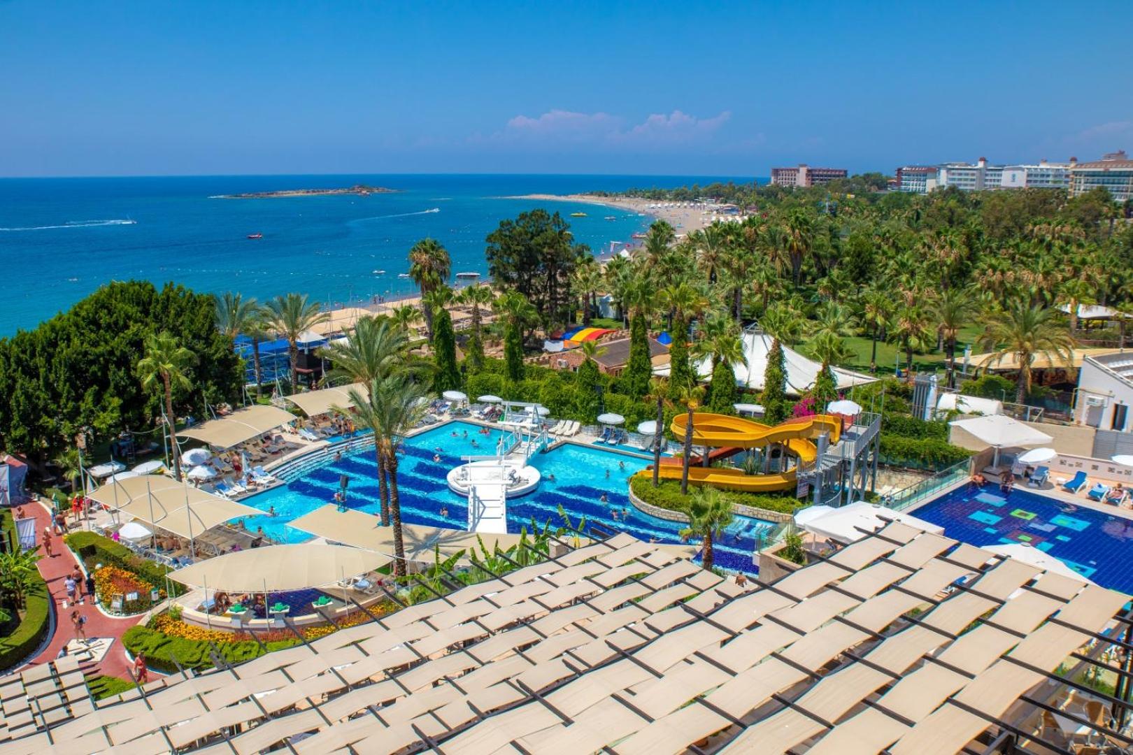 Sealife Buket Resort & Beach panorāmas skats uz baseinu kompleksu, ūdens slidkalniņiem un Vidusjūras piekrasti Alānijas reģionā, Turcijā.