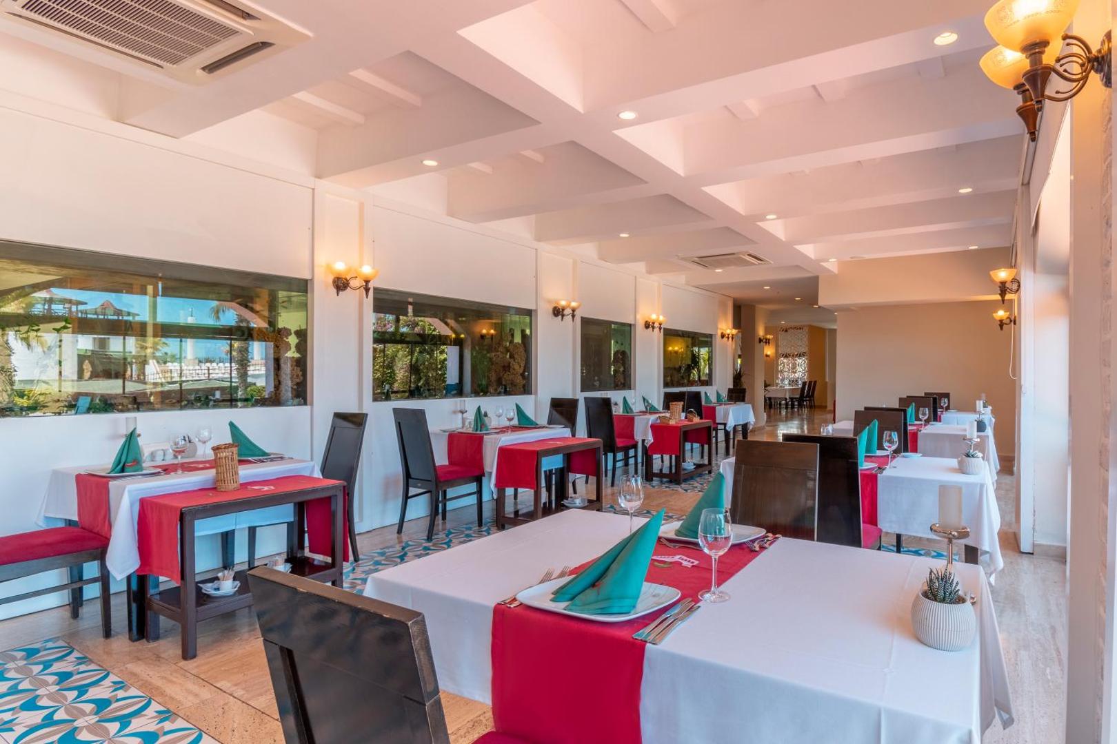 Moderns Emelda Sun Club restorāns ar akvārijiem sienās, sarkaniem galdautiem un gaišu interjeru