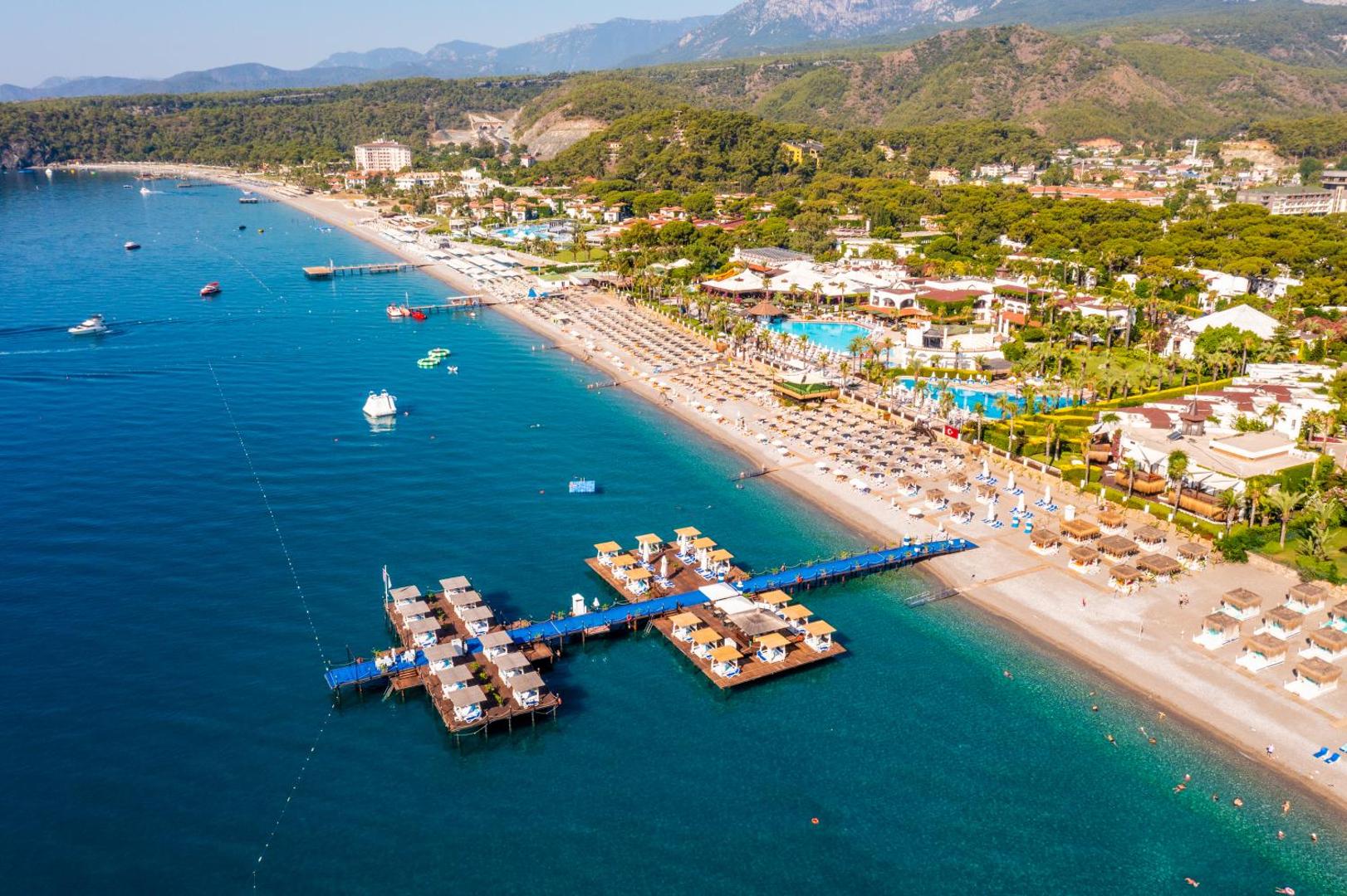 Emelda Sun Club panorāmas skats no putna lidojuma uz pludmali un koka piestātni ar atpūtas zonām Kemeras piekrastē