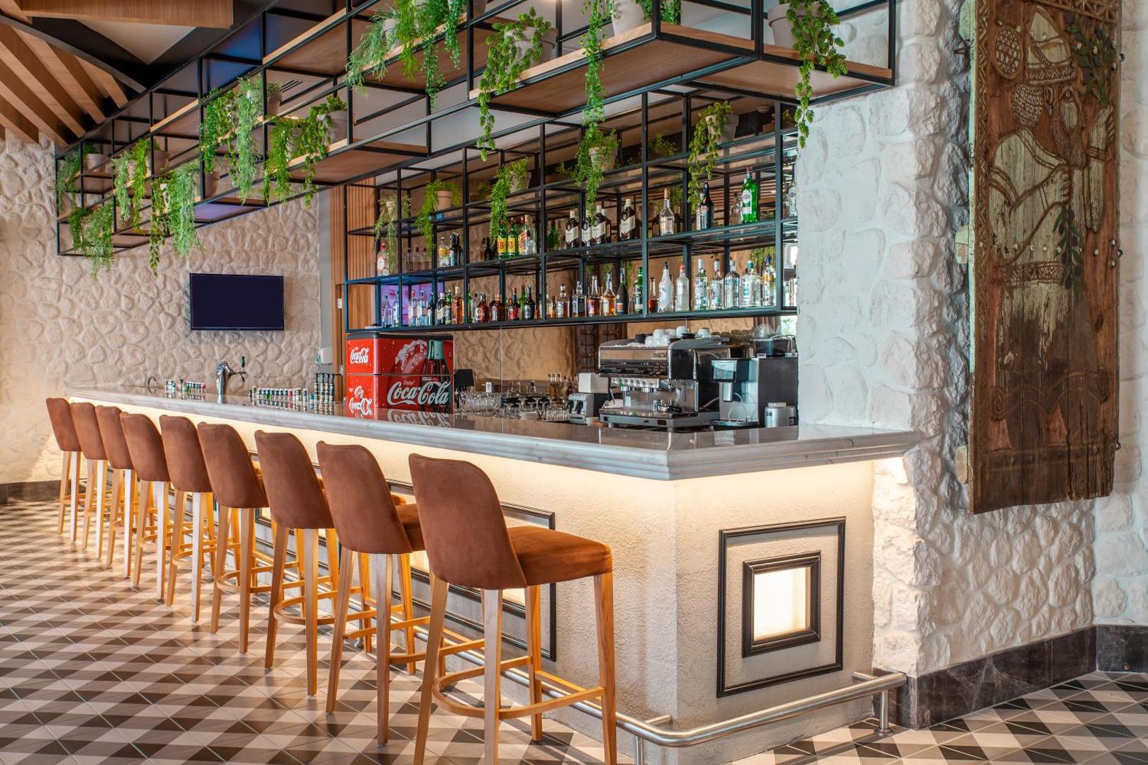 Side Royal Style viesnīcas lobby bārs ar modernu interjeru, akmens sienām un augstiem bāra krēsliem pie gaišas marmora letes