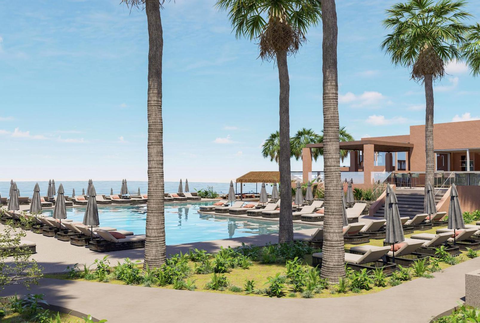 Skats caur palmām uz Blue Sea Beach Affiliated By Melia baseinu un jūras horizontu Krētā — apstādījumi un atpūtas krēsli