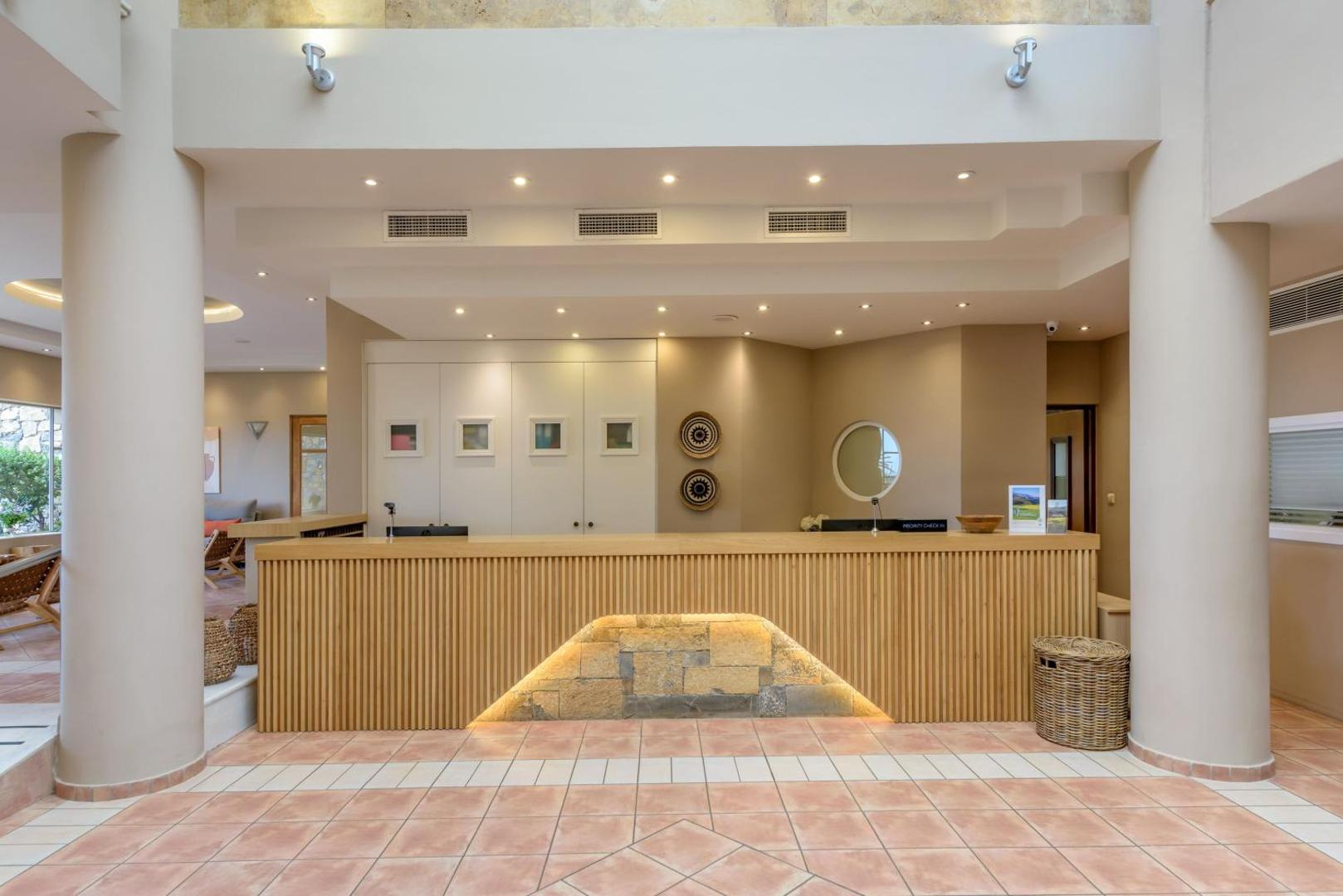 Blue Sea Beach Affiliated By Melia viesnīcas recepcijas lete ar koka apdari un akmens elementiem gaišā, modernā vestibilā
