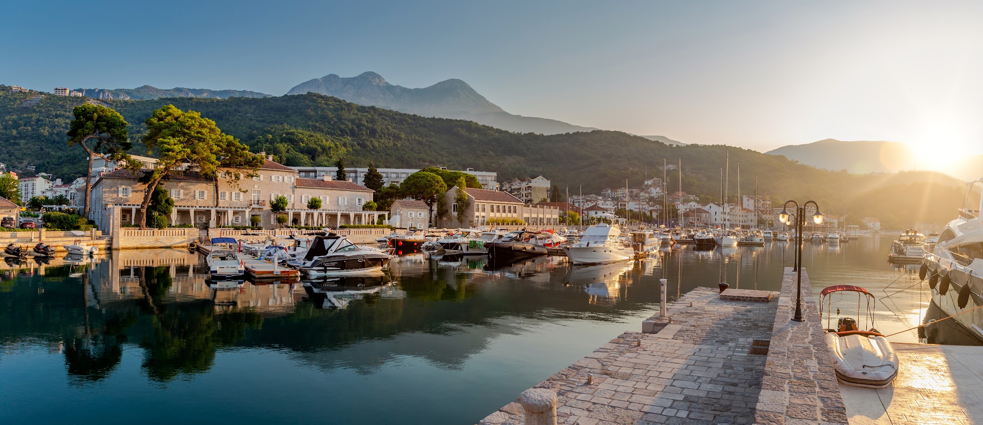 Panorāmas skats uz Lazure Hotel & Marina jahtu ostu un kalniem saullēktā Melnkalnes piekrastē