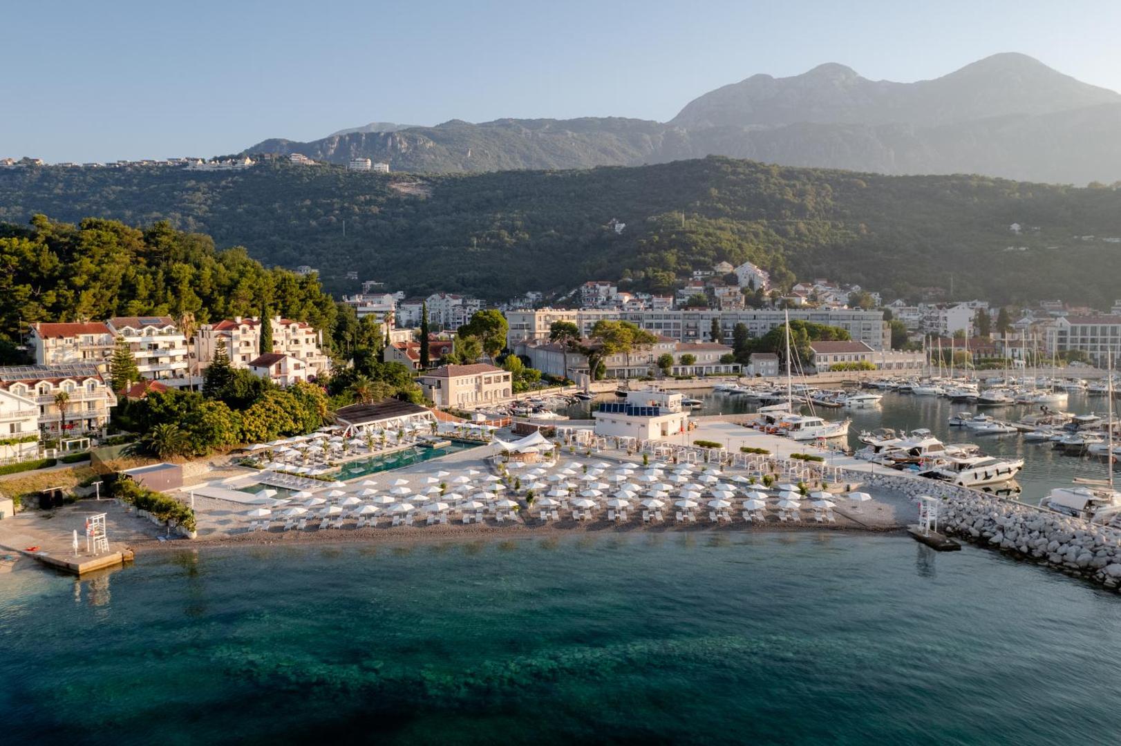 Lazure Hotel & Marina privātā pludmale ar baltiem saulessargiem un kristāldzidru ūdeni Melnkalnē