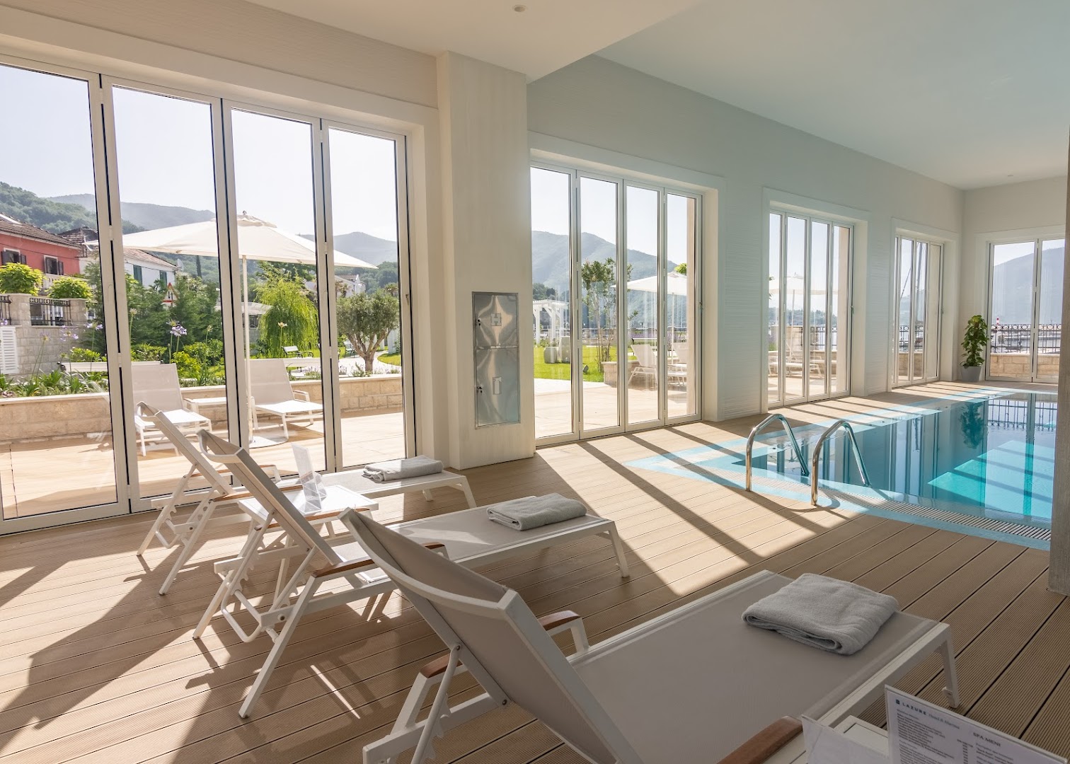 Lazure Hotel & Marina spa atpūtas telpa ar zviļņiem pie iekštelpu baseina un skatu uz kalniem caur lielajiem logiem