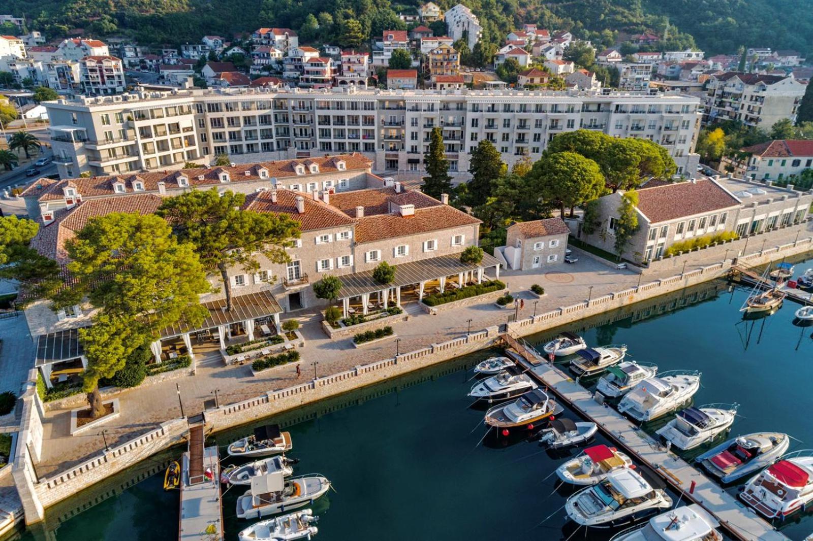 Lazure Hotel & Marina skats no putna lidojuma uz vēsturisko akmens ēku un jahtu piestātni Melnkalnes piekrastē