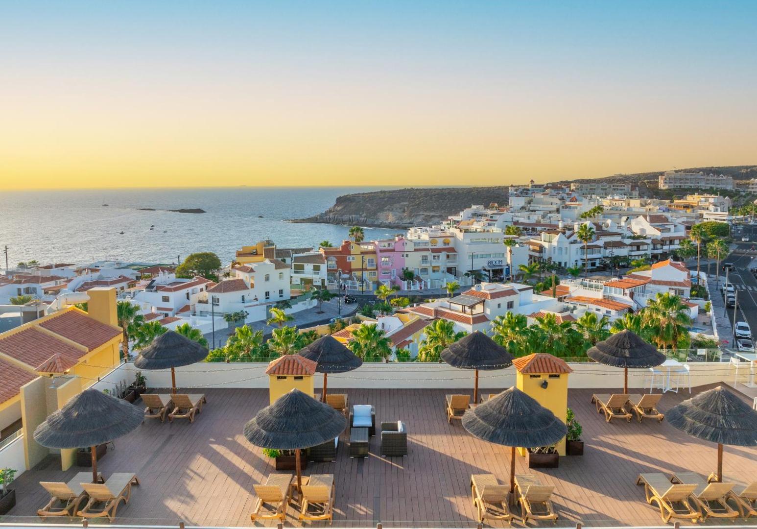 Hovima Jardin Caleta jumta terase ar sauļošanās krēsliem, saulessargiem un skatu uz okeānu un pilsētu Tenerifē