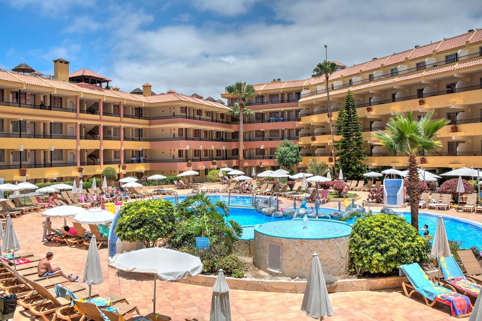 Hovima Jardin Caleta āra baseinu komplekss ar bērnu zonu, palmām un saulessargiem dienas laikā Tenerifes dienvidos.