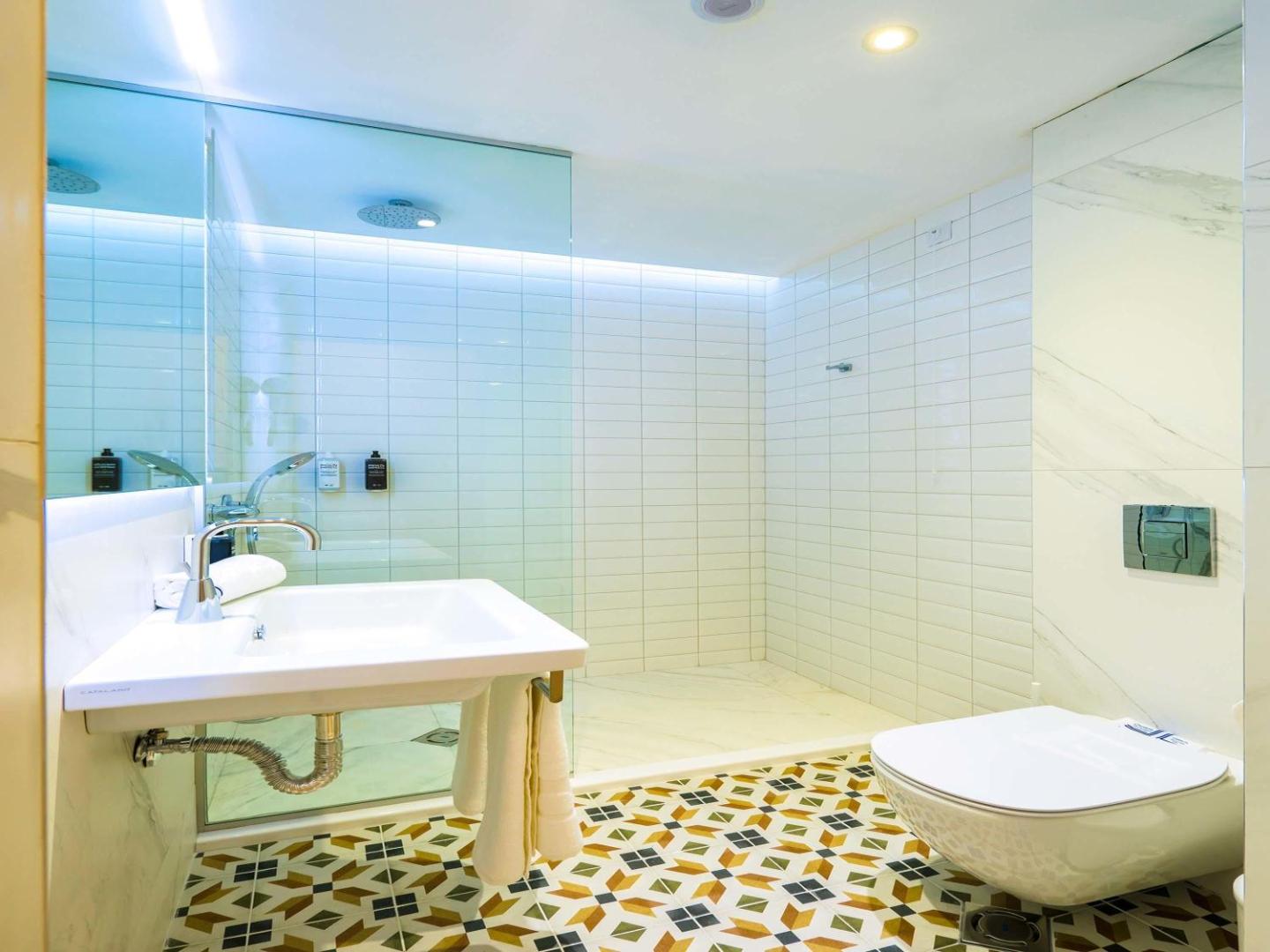 Moderna Ibis Styles Golden Sands Roomer Hotel numura vannas istaba ar gaišām flīzēm, rakstainu grīdu un plašu dušas zonu