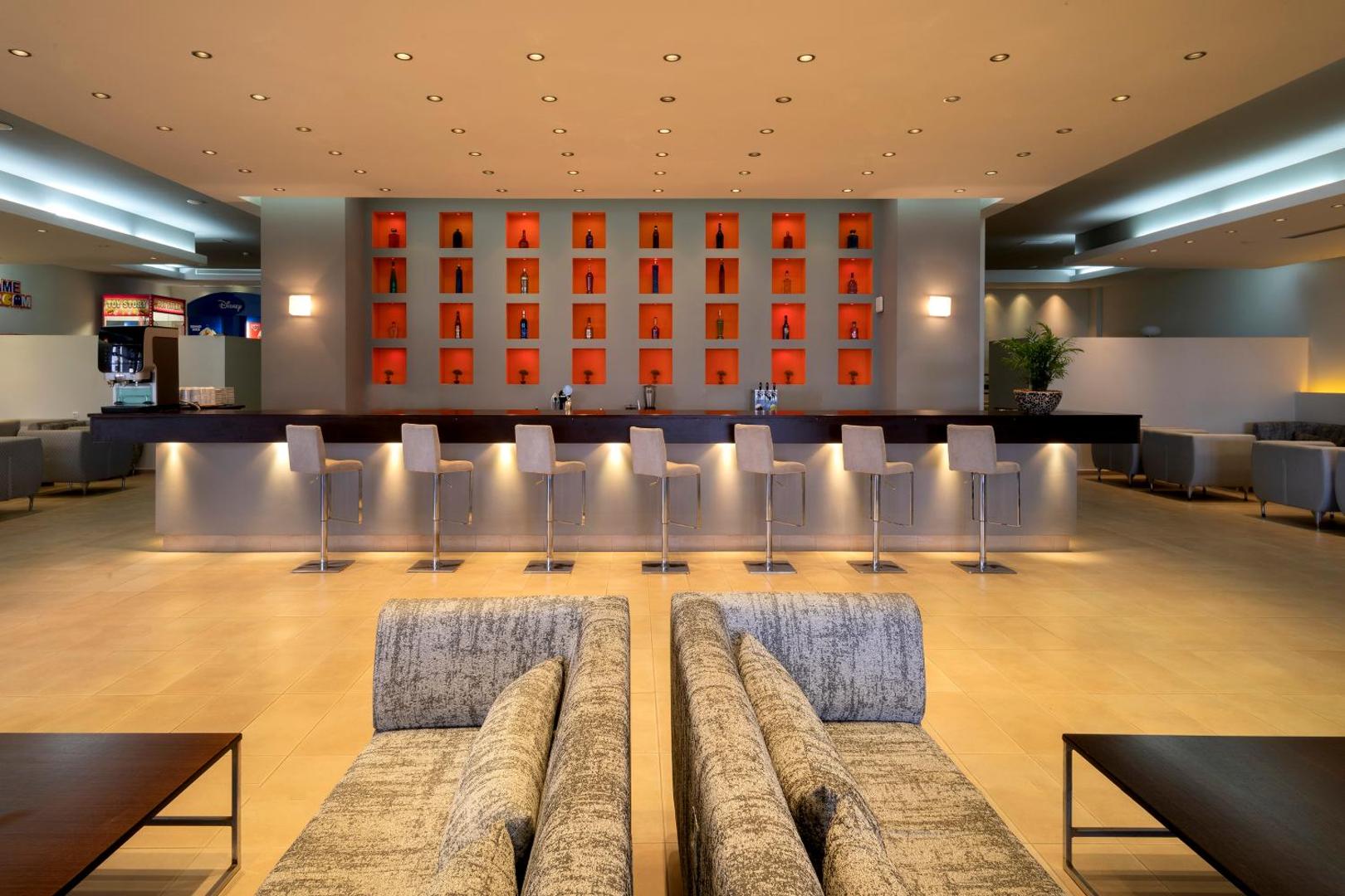 Sol by Melia Cosmopolitan Rhodes modernais lobby bārs ar augstiem krēsliem, izgaismotu leti un ērtiem dīvāniem Rodas salā.