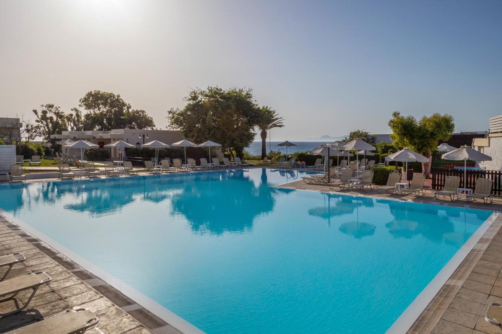 Sol by Melia Cosmopolitan Rhodes baseins ar skatu uz Egejas jūru, saulessargiem un palmām Rodas piekrastē