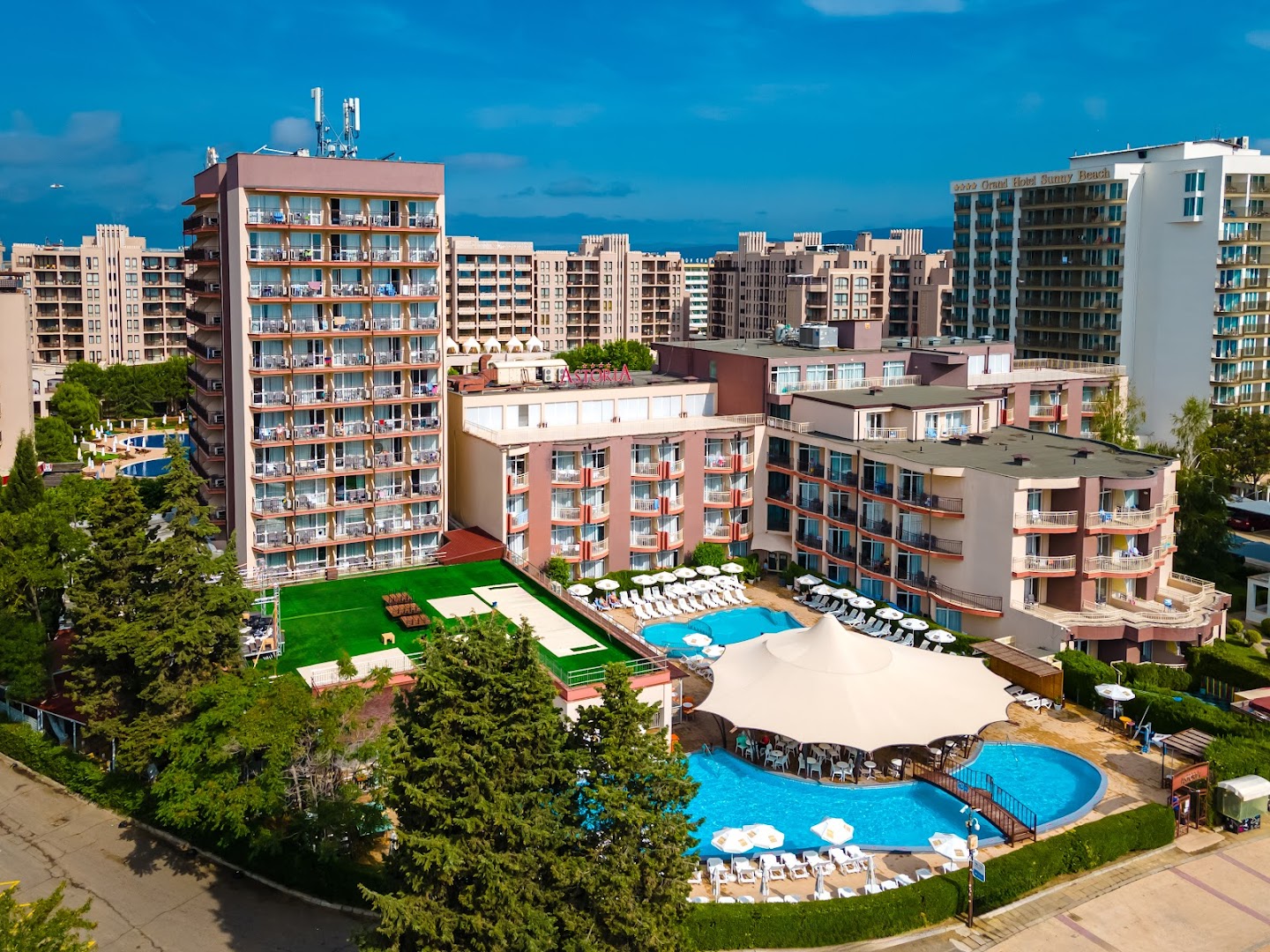 MPM Hotel Astoria skats no augšas uz āra baseinu kompleksu un viesnīcas korpusiem Saulainajā krastā, Bulgārijā