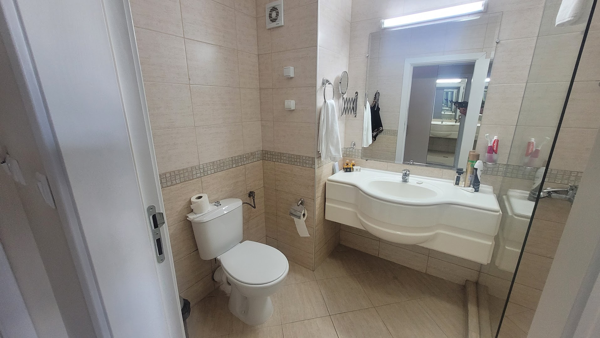 MPM Hotel Astoria numura vannasistaba ar izlietni, spoguli un tualeti — gaišs un tīrs interjers viesu ērtībām