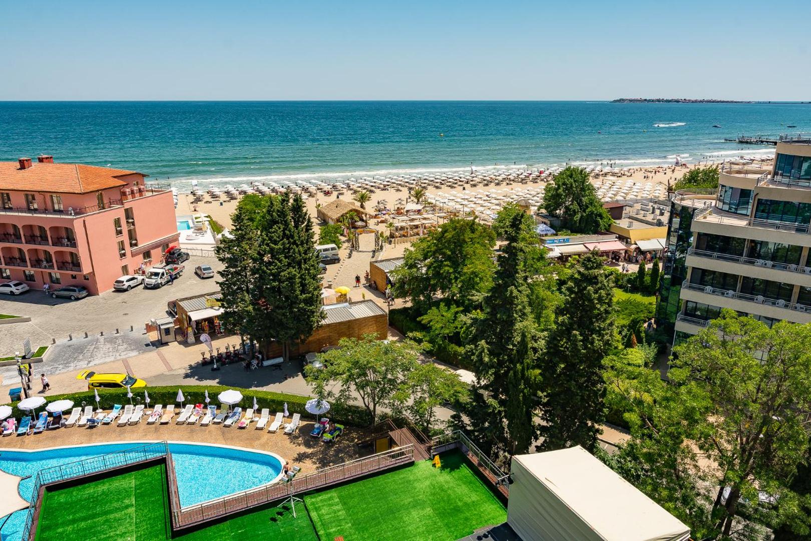 Skats no MPM Hotel Astoria uz Melno jūru un plašo smilšu pludmali ar saulessargiem Saulainā krasta kūrortā