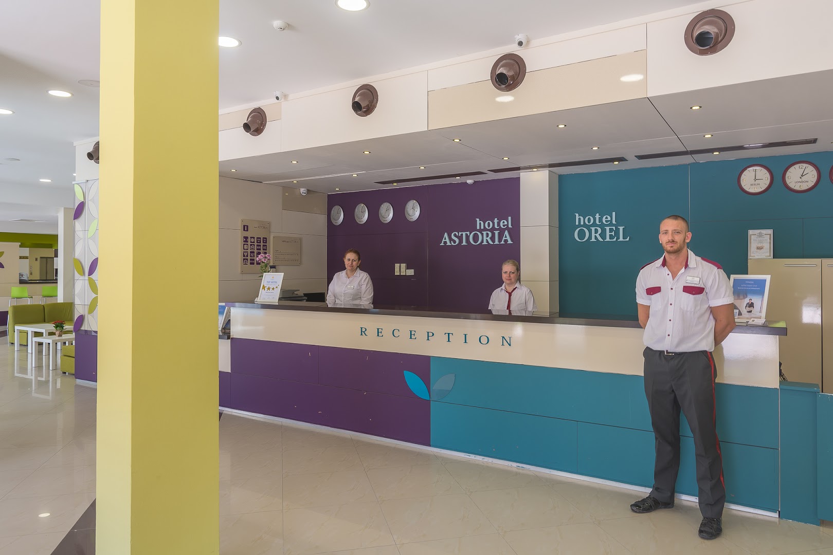 MPM Hotel Astoria un Hotel Orel kopīgā recepcijas zona Saulainajā krastā, Bulgārijā — moderns vestibils ar viesmīlīgu personālu un košu interjeru