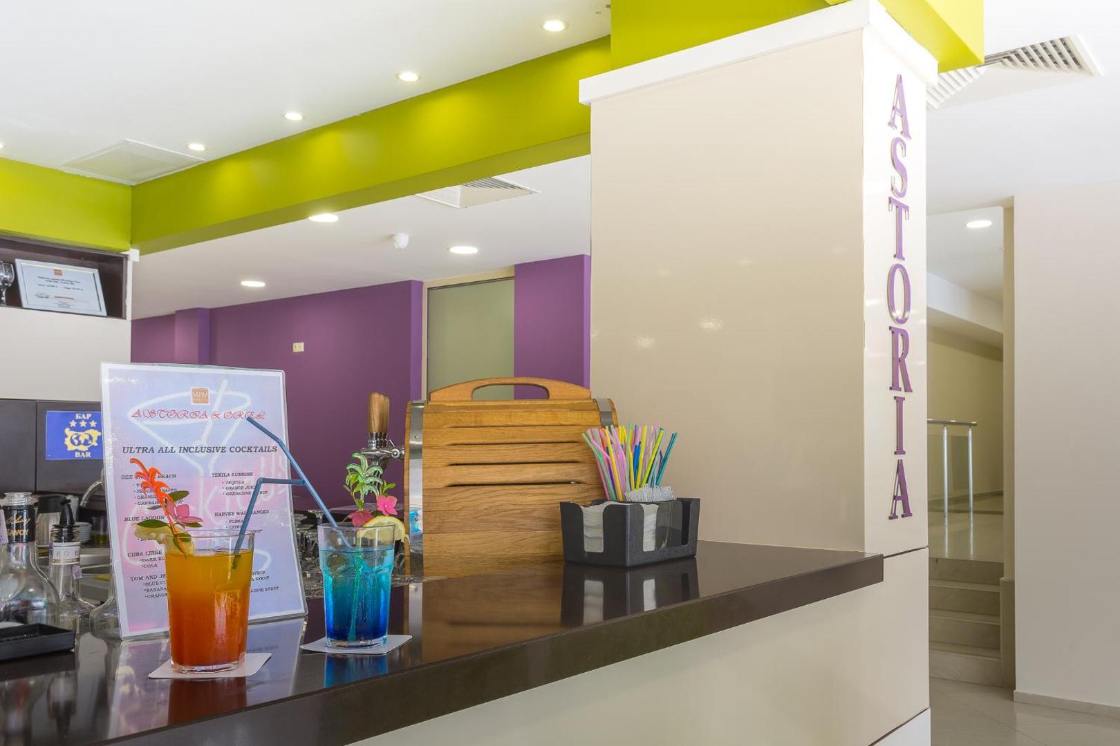 MPM Hotel Astoria bāra lete ar krāsainiem kokteiļiem — ultra all-inclusive dzērienu piedāvājums un moderna atpūtas zona viesnīcas iekštelpās