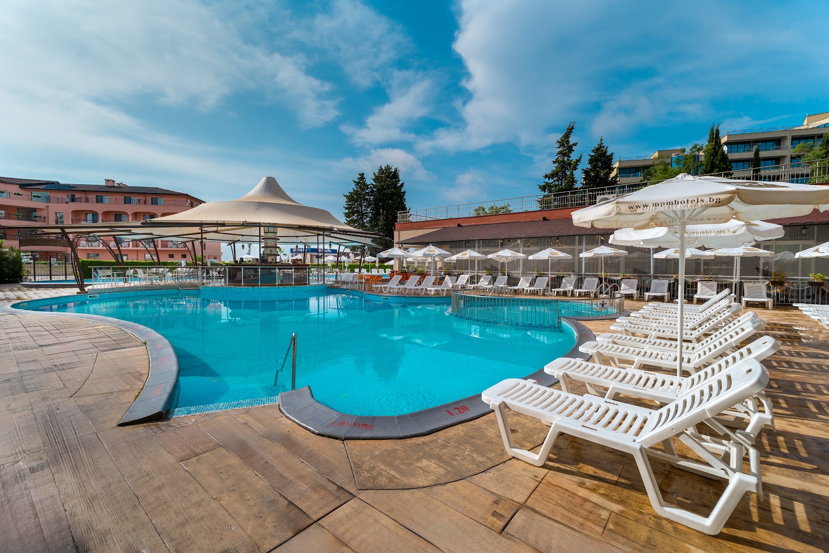 MPM Hotel Astoria atpūtas zona pie baseina ar baltiem sauļošanās krēsliem un baseina bāru Saulainajā krastā, Bulgārijā