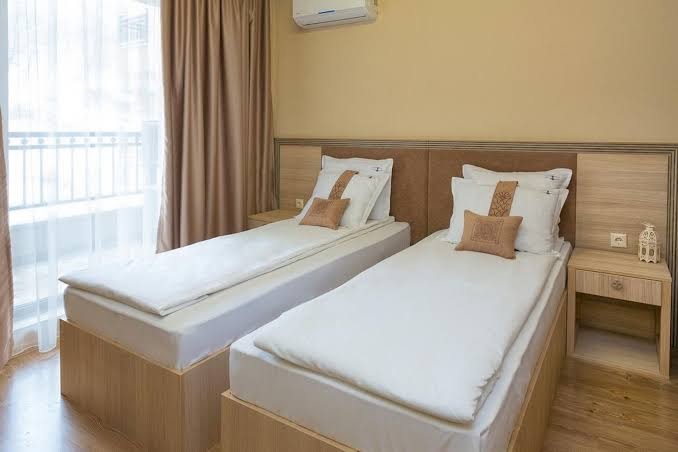 Argisht Partez Hotel guļamistaba ar divām atsevišķām gultām, gaišām mēbelēm un izeju uz balkonu kūrortā Zelta Smiltis