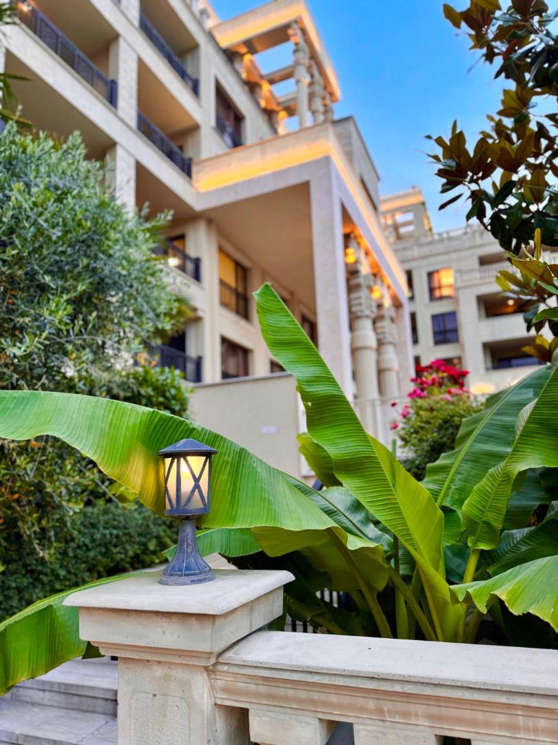 Argisht Partez Hotel modernā arhitektūra vakarā Zelta smiltīs — izgaismota fasāde ar balkoniem un eksotiskiem augiem dārzā