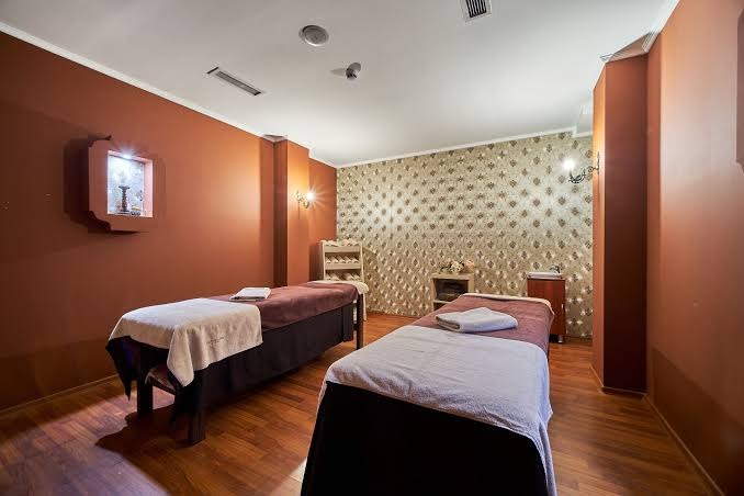 Bilyana Beach Hotel spa centrs ar diviem masāžas galdiem un siltu apgaismojumu relaksējošām procedūrām