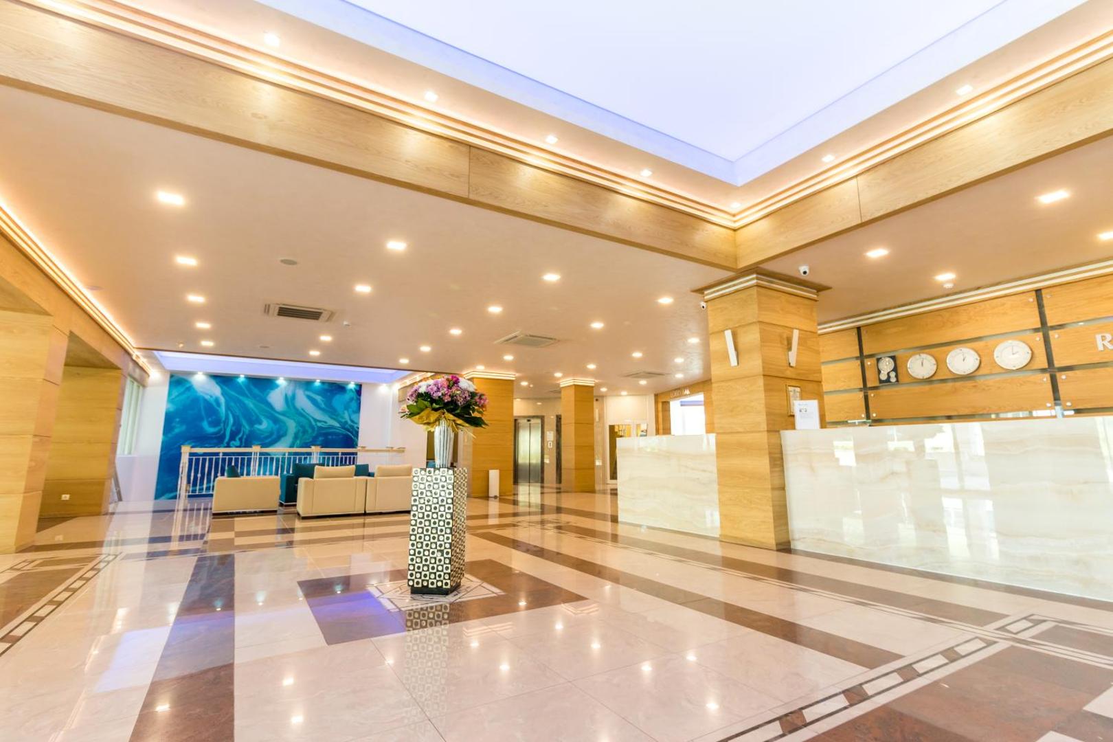 Bilyana Beach Hotel recepcijas zona ar marmora grīdām, koka apdari un modernu apgaismojumu Nesebāras kūrortā