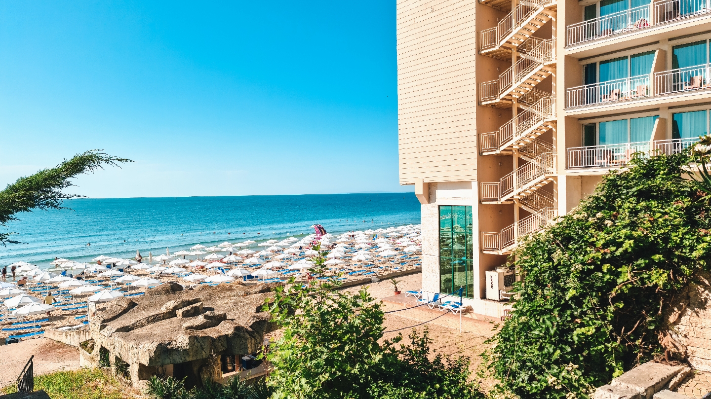 Skats no Bilyana Beach Hotel uz plašo pludmali ar simtiem saulessargu un zilo jūru Nesebāras kūrortā Bulgārijā