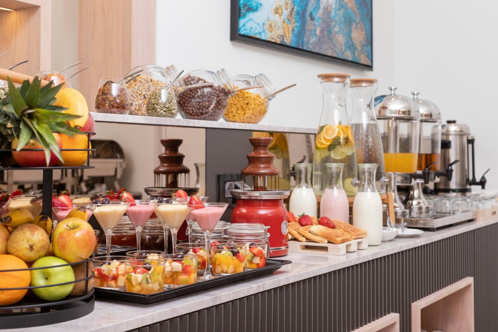 Bagātīga brokastu bufete Momentum by Aycon Boutique Hotel ar augļiem, desertiem un šokolādes strūklaku viesiem Melnkalnē
