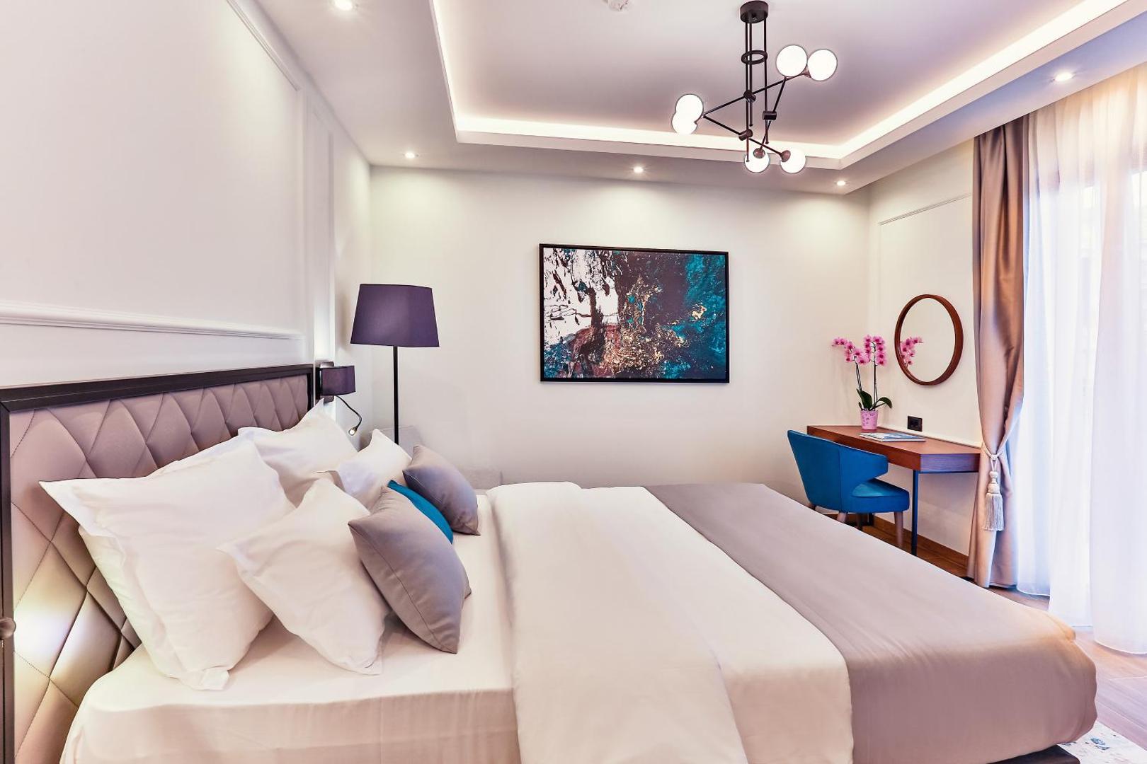 Momentum by Aycon Boutique Hotel numura interjers ar rakstāmgaldu, zilu krēslu, modernu lustru un mākslas darbu pie sienas