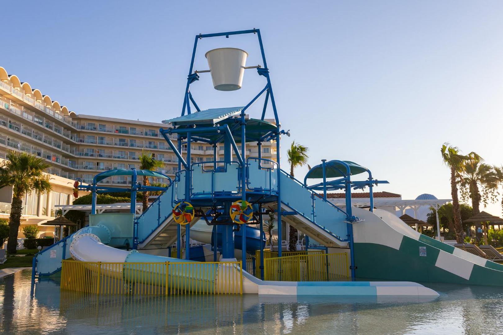 Pegasos Beach Hotel & Resort akvaparks ar slidkalniņiem un baseinu pie viesnīcas ēkas Rodā — plaša atpūtas zona ģimenēm