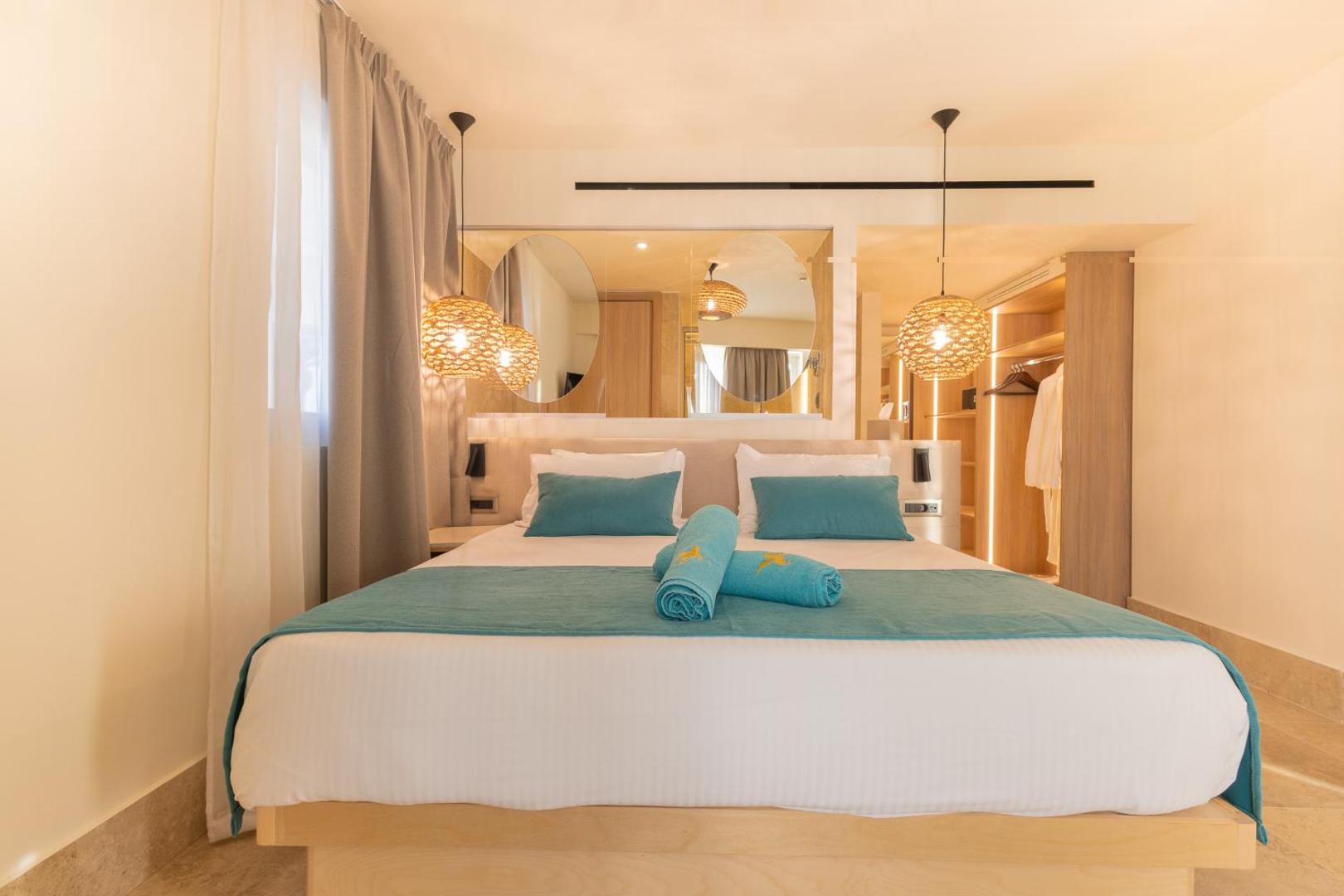 Pegasos Beach Hotel moderns divvietīgs numurs ar gaišām koka mēbelēm, dekoratīviem gaismekļiem un tirkīza krāsas akcentiem Faliraki kūrortā