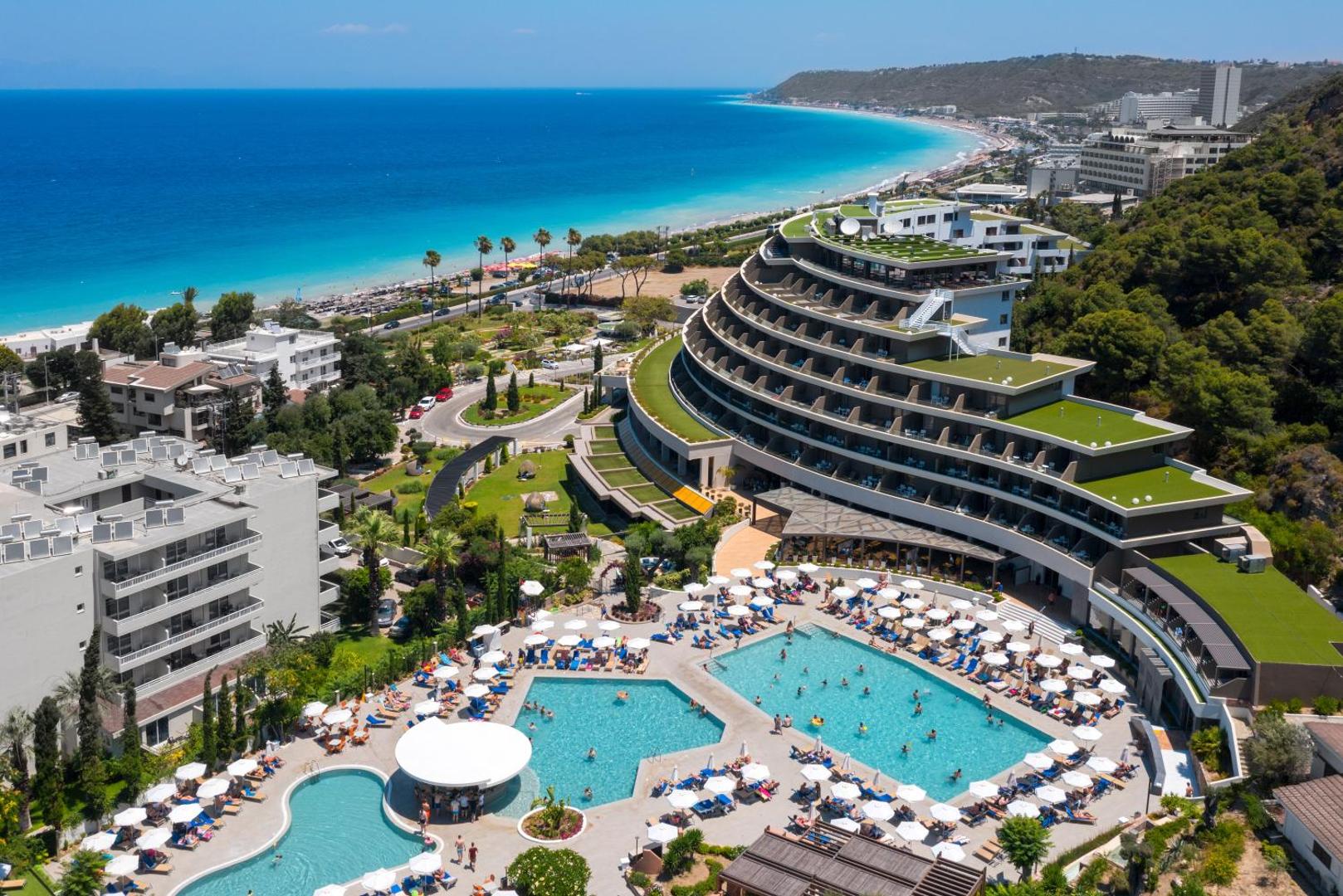 Olympic Palace Resort Hotel skats no putna lidojuma Rodas salā — baseinu komplekss, viesnīcas arhitektūra un Egejas jūras ...