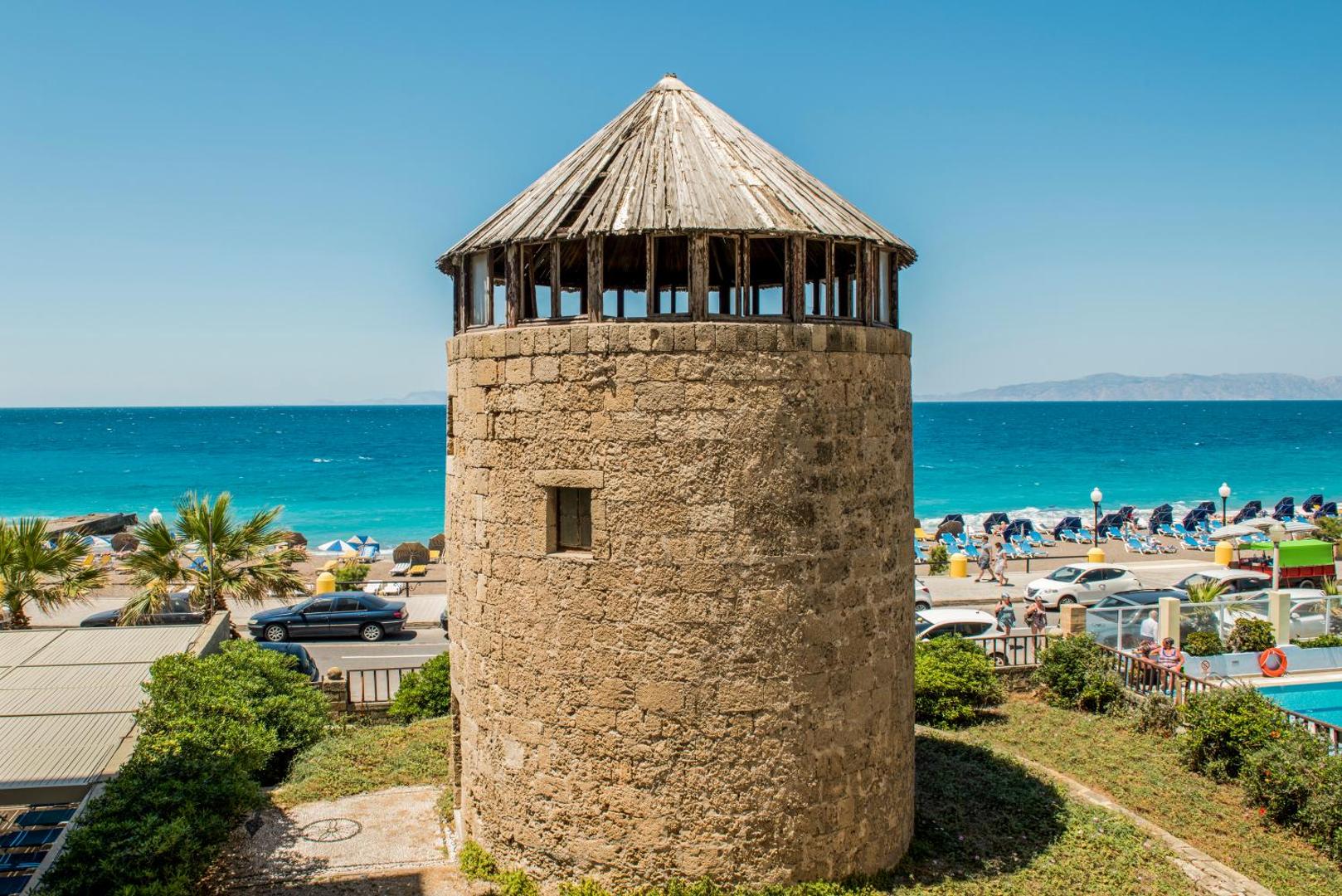 Vēsturisks akmens tornis pie Mitsis La Vita Beach Hotel Rodas piekrastē ar skatu uz pludmali un jūru
