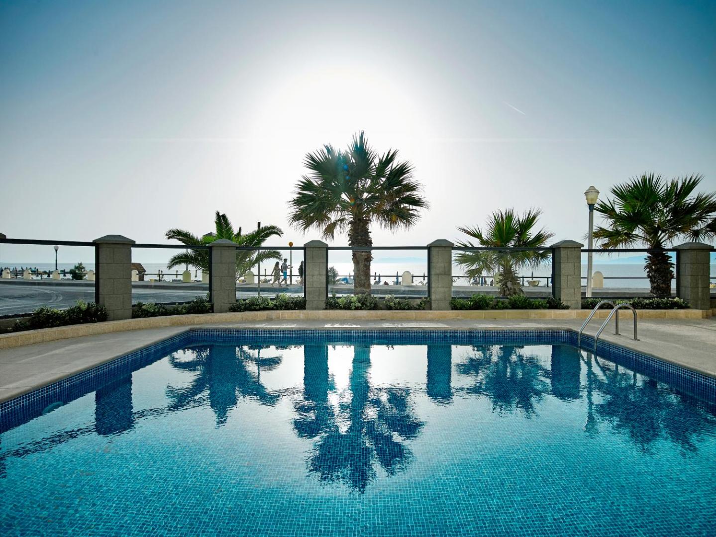 Mitsis La Vita Beach Hotel āra baseins Rodas pilsētā ar skatu uz jūru un palmām saules gaismā