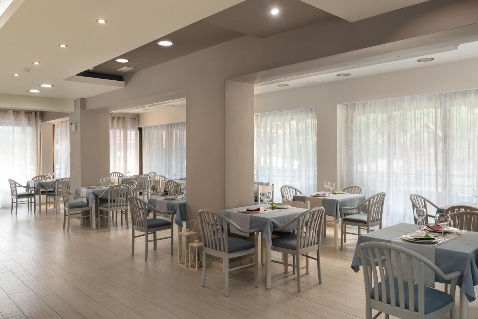 Matoula Beach Hotel restorāna iekštelpas ar modernu dizainu un elegantiem galdiem — plaša un gaiša brokastu un vakariņu zāle