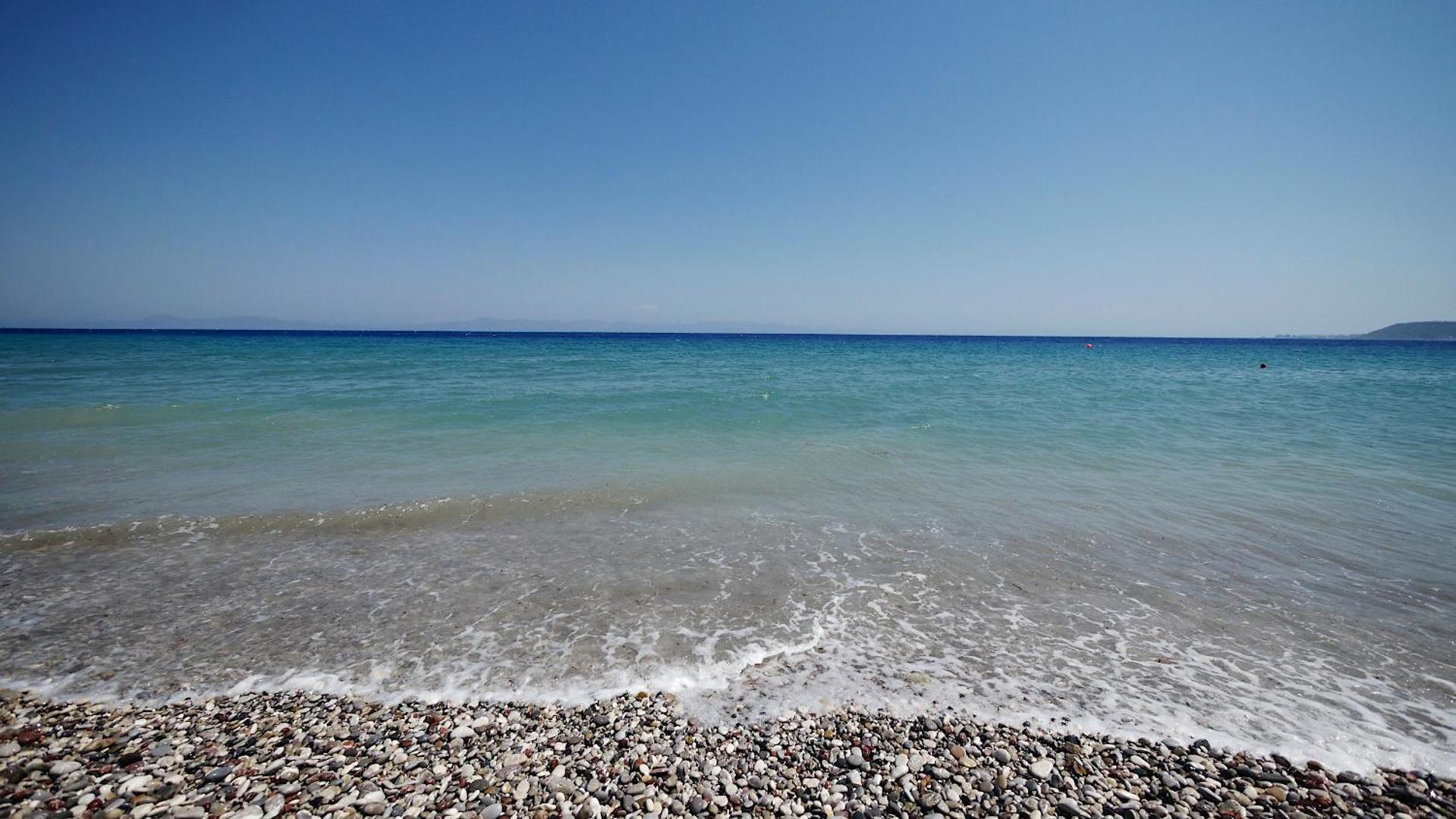 Matoula Beach Hotel oļu pludmale ar dzidru, zilu ūdeni Rodas salā — plašs skats uz horizontu saulainā dienā