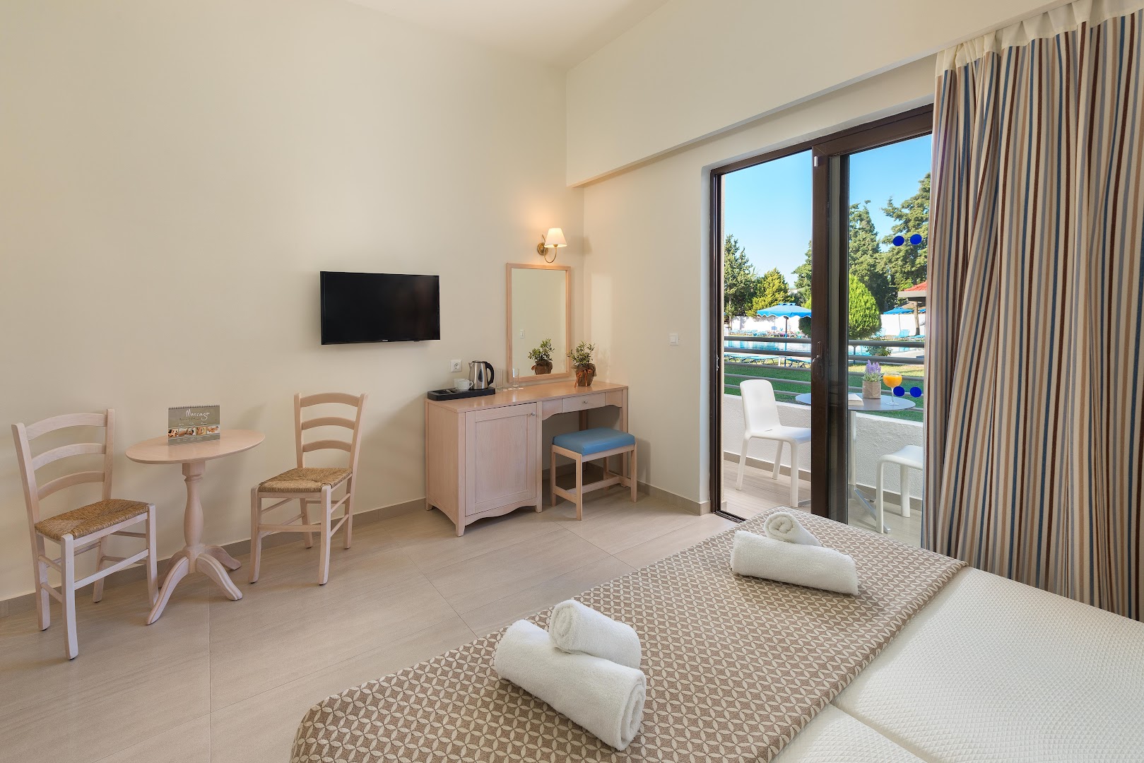 Gaišs Matoula Beach Hotel numurs ar divguļamo gultu, darba galdu un izeju uz terasi ar skatu uz baseinu