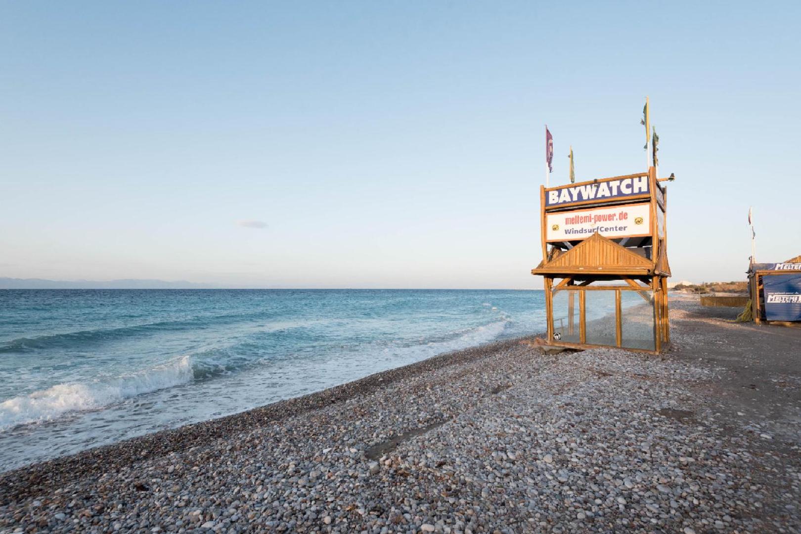Matoula Beach Hotel oļu pludmale Rodā ar glābēju torni un vindsērfinga centru pie zilās Egejas jūras krasta līnijas