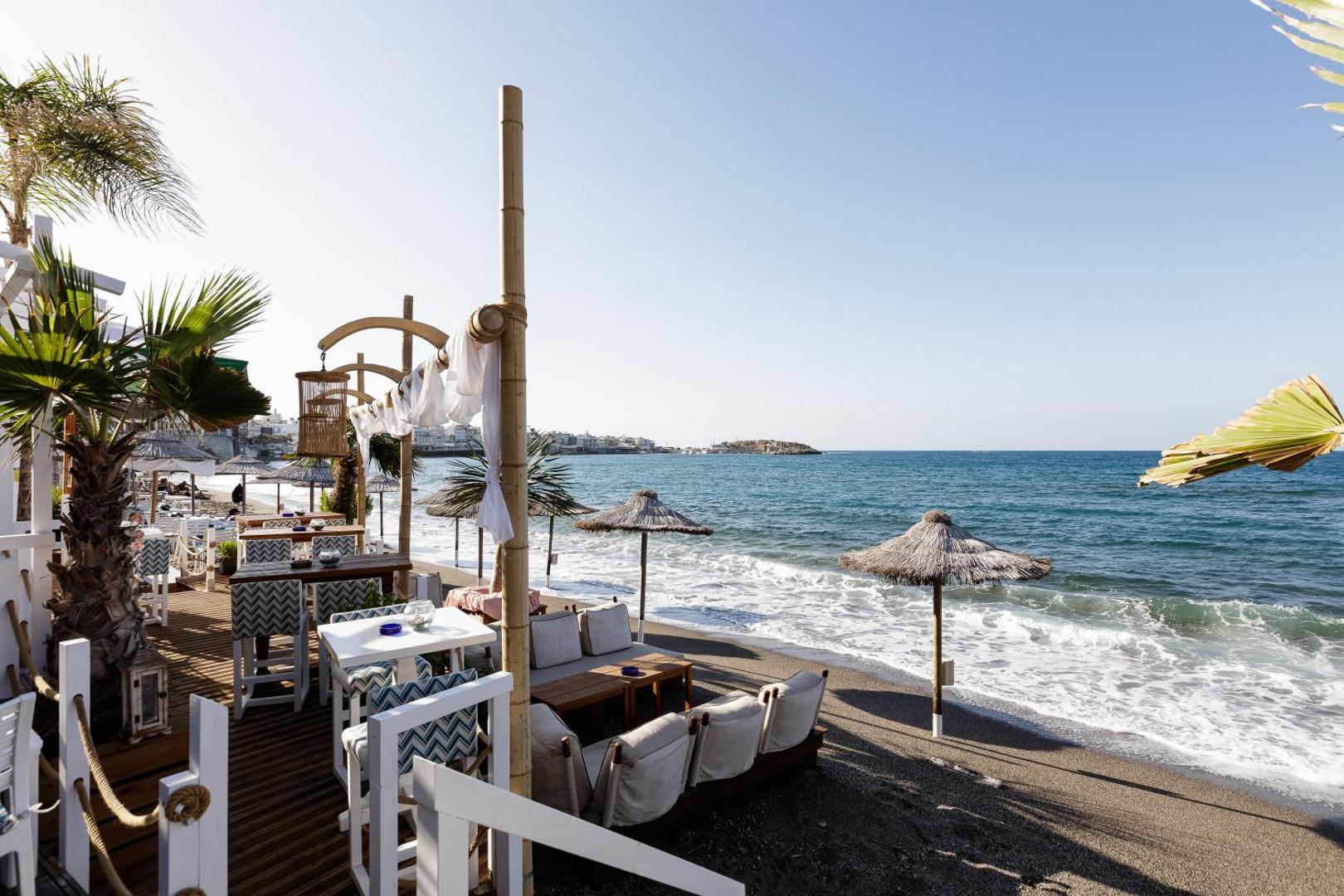 Kahlua Boutique Hotel pludmales bāra terase ar stilīgām mēbelēm, bambusa dekorācijām un skatu uz zilo Vidusjūru Krētā