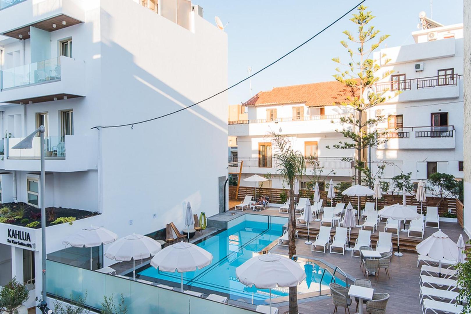 Kahlua Boutique Hotel āra baseins Hersonisā, Krētā — skats no augšas uz sauļošanās zonu ar baltiem saulessargiem un atpūtas krēsliem