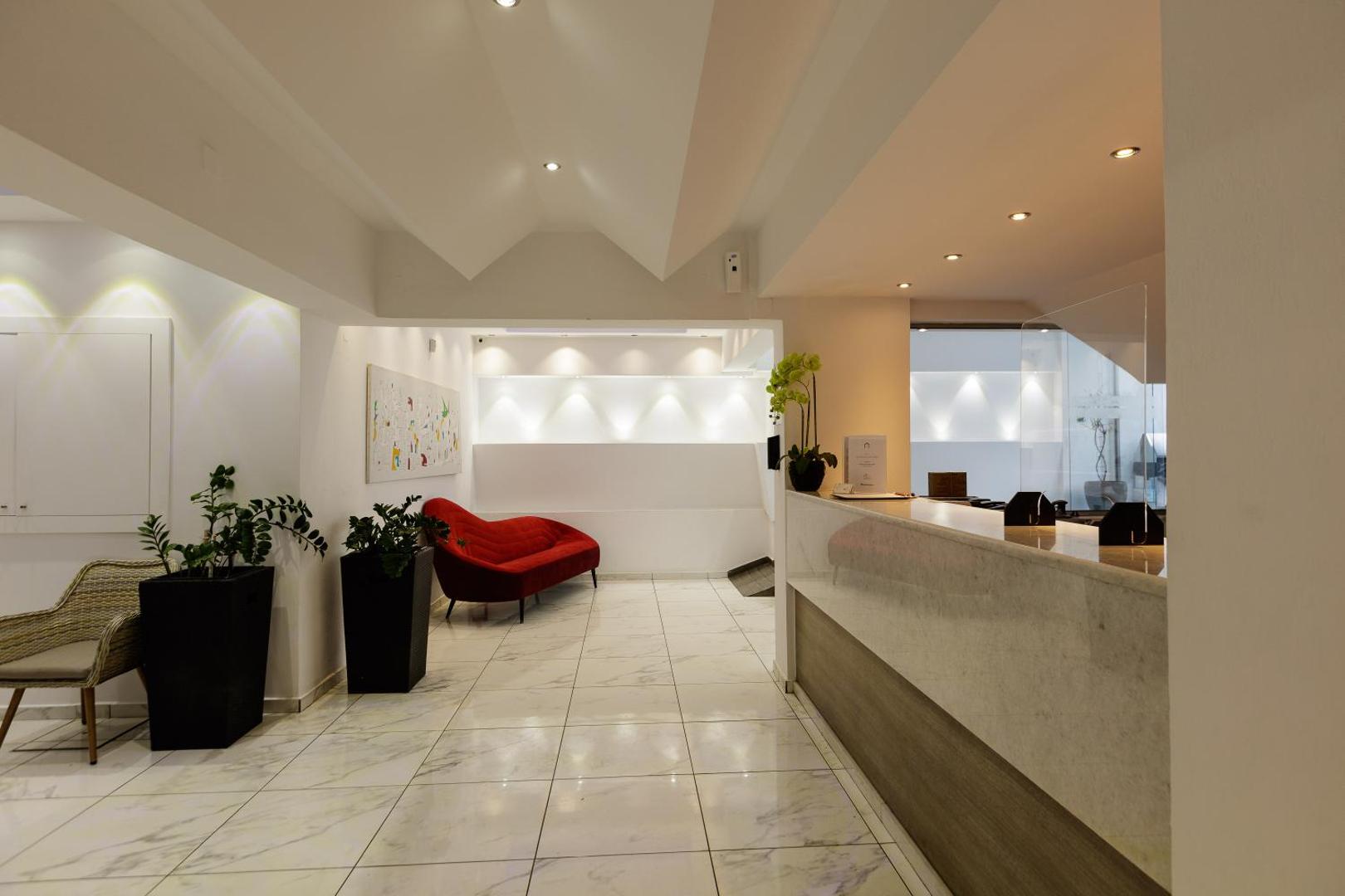 Kahlua Boutique Hotel vestibila atpūtas zona ar sarkanu dizaina dīvānu un marmora flīzēm — elegants interjers Hersonisas boutique viesnīcā