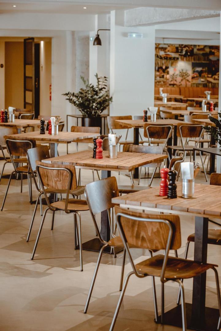 Cook's Club Hersonissos restorāna Cantina interjers ar koka galdiem un industriāla stila krēsliem — moderna un mājīga atmosfēra